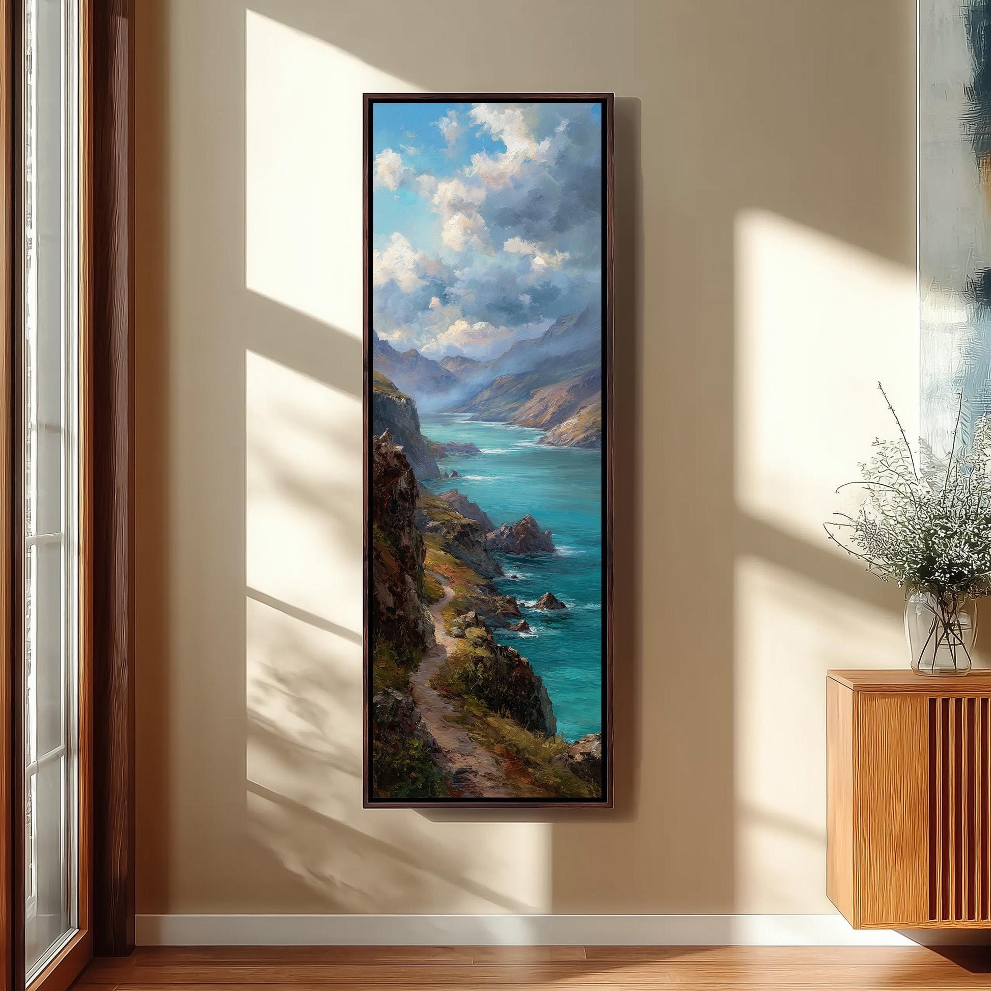 a large framed painting of a scenic coastal landscape, with a winding path leading to a turquoise sea and mountains in the background.