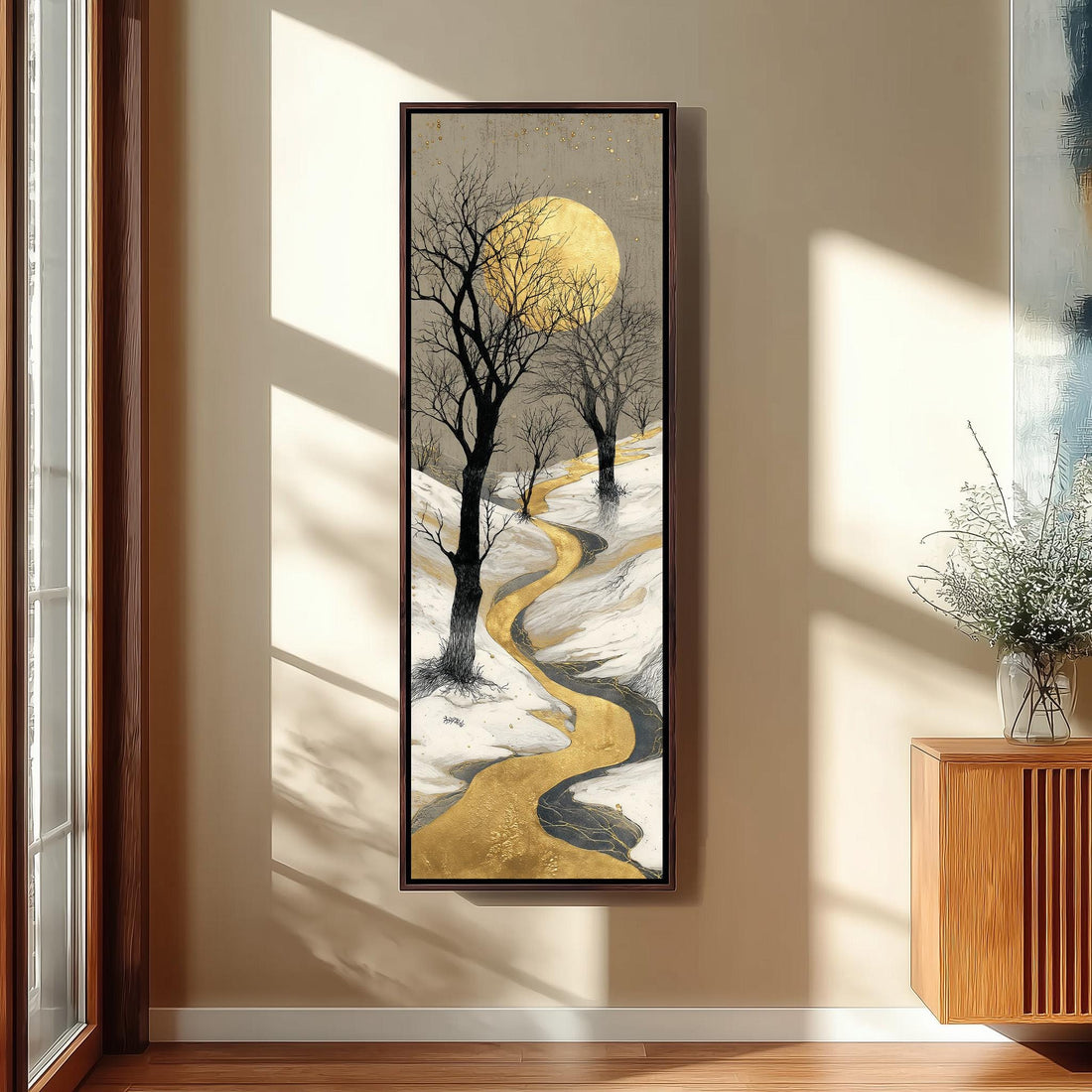 a large, framed painting of a snowy landscape with a winding path, a full moon, and bare trees. The painting is hanging on a wall in a modern, minimalist kitchen setting.