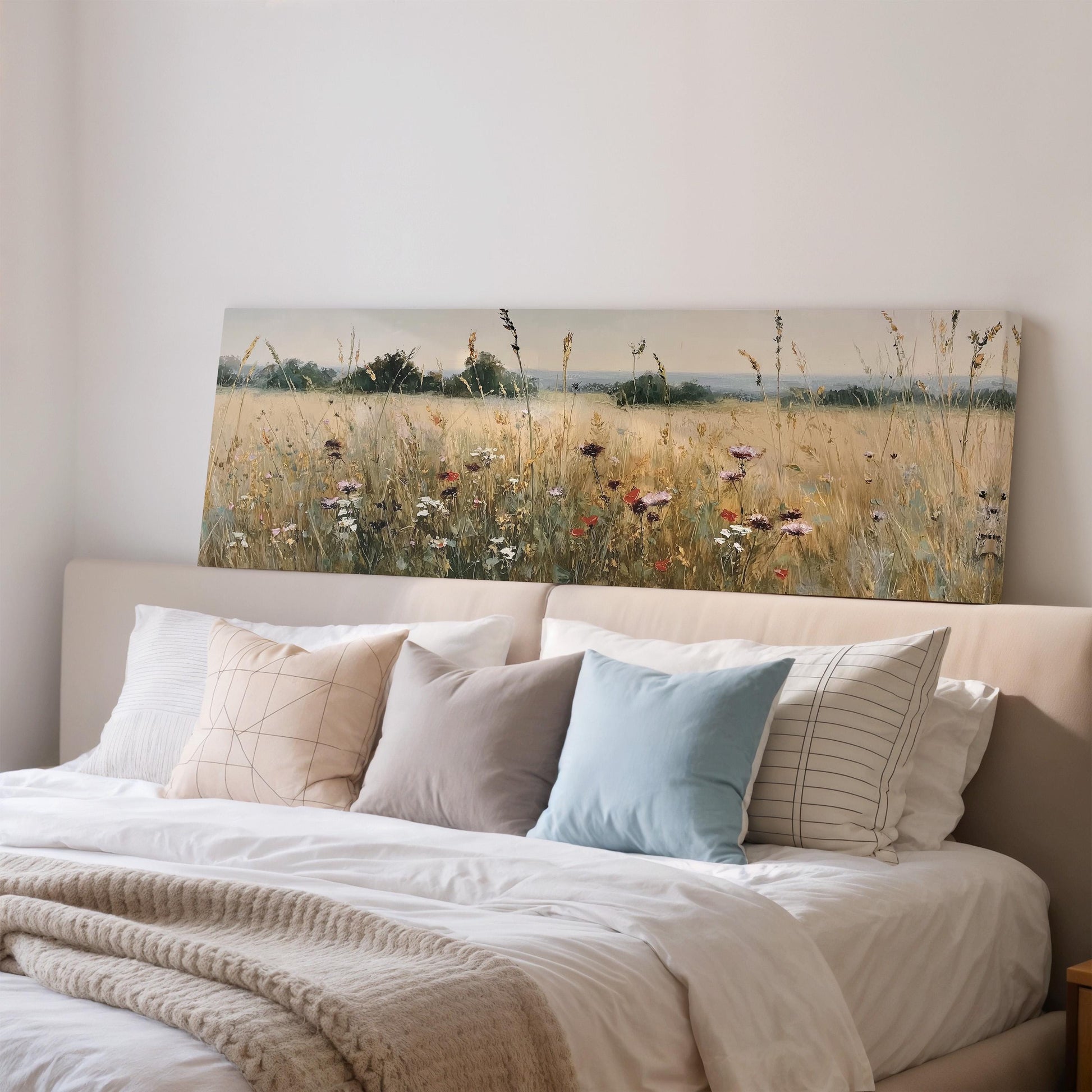 a large painting of a field of flowers hanging on a wall above a bed with white bedding and pillows.