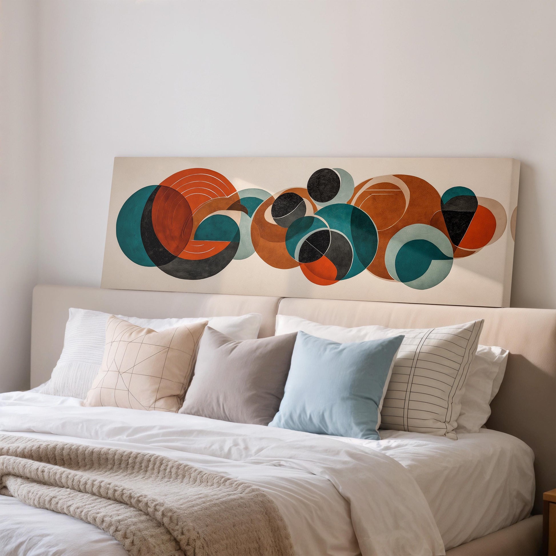 a large abstract painting hanging on a wall above a bed with white pillows and a gray blanket.