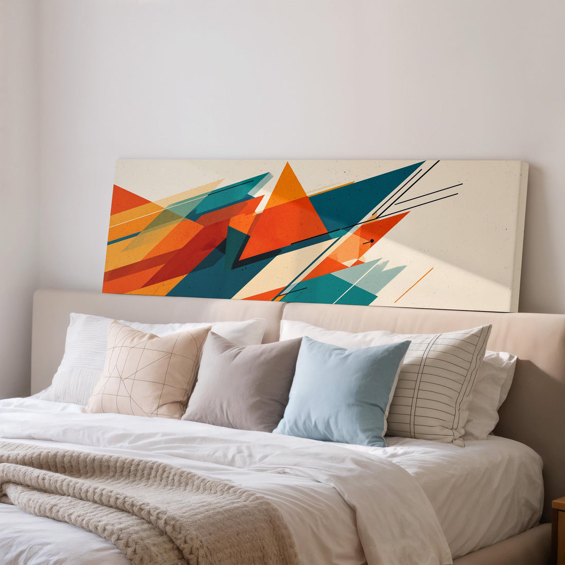 a large abstract painting hanging on a wall above a bed with white pillows and a gray blanket.