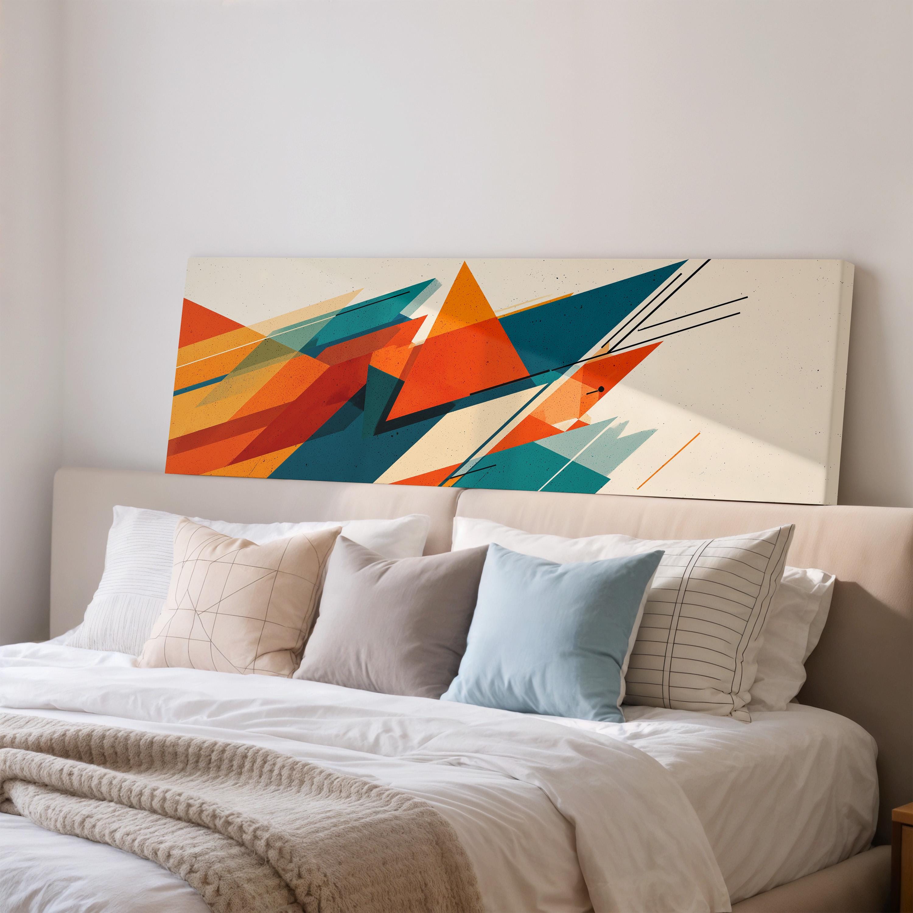 a large abstract painting hanging on a wall above a bed with white pillows and a gray blanket.