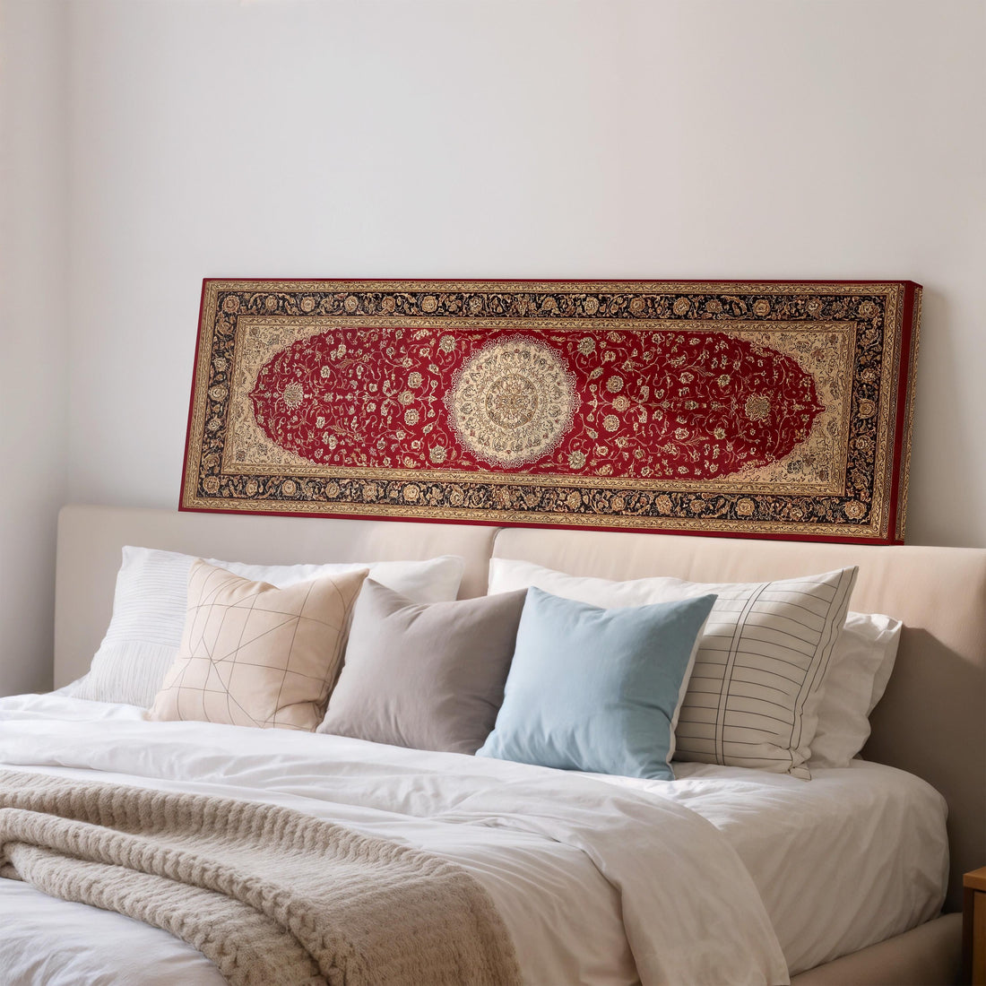 a large, ornate red and gold rug hanging on a white wall above a brown sofa with two pillows.