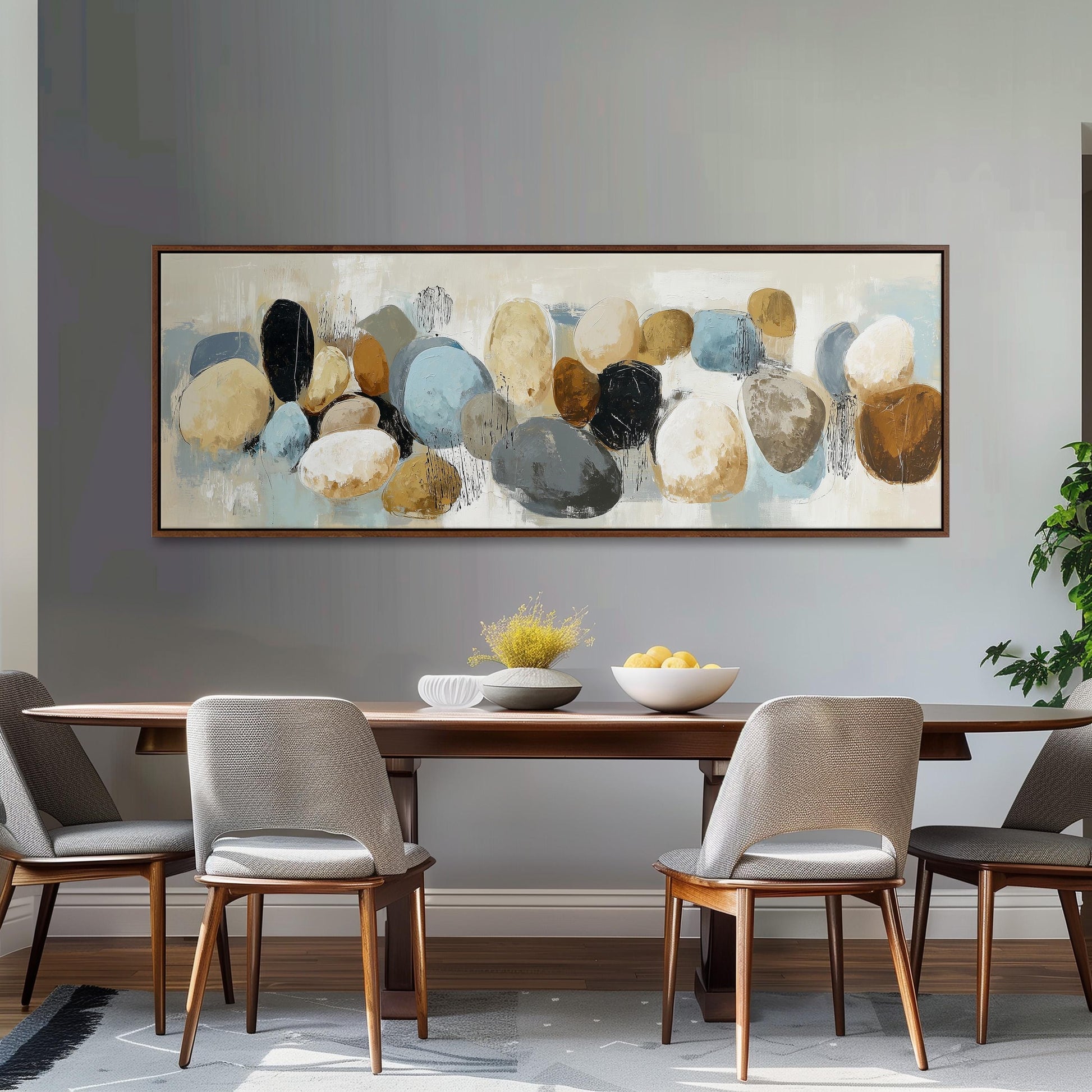 a dining room with a large painting of various colored rocks hanging on the wall above a wooden dining table with four chairs. The table is set with a bowl of fruit and a vase of flowers, creating a cozy and inviting atmosphere.