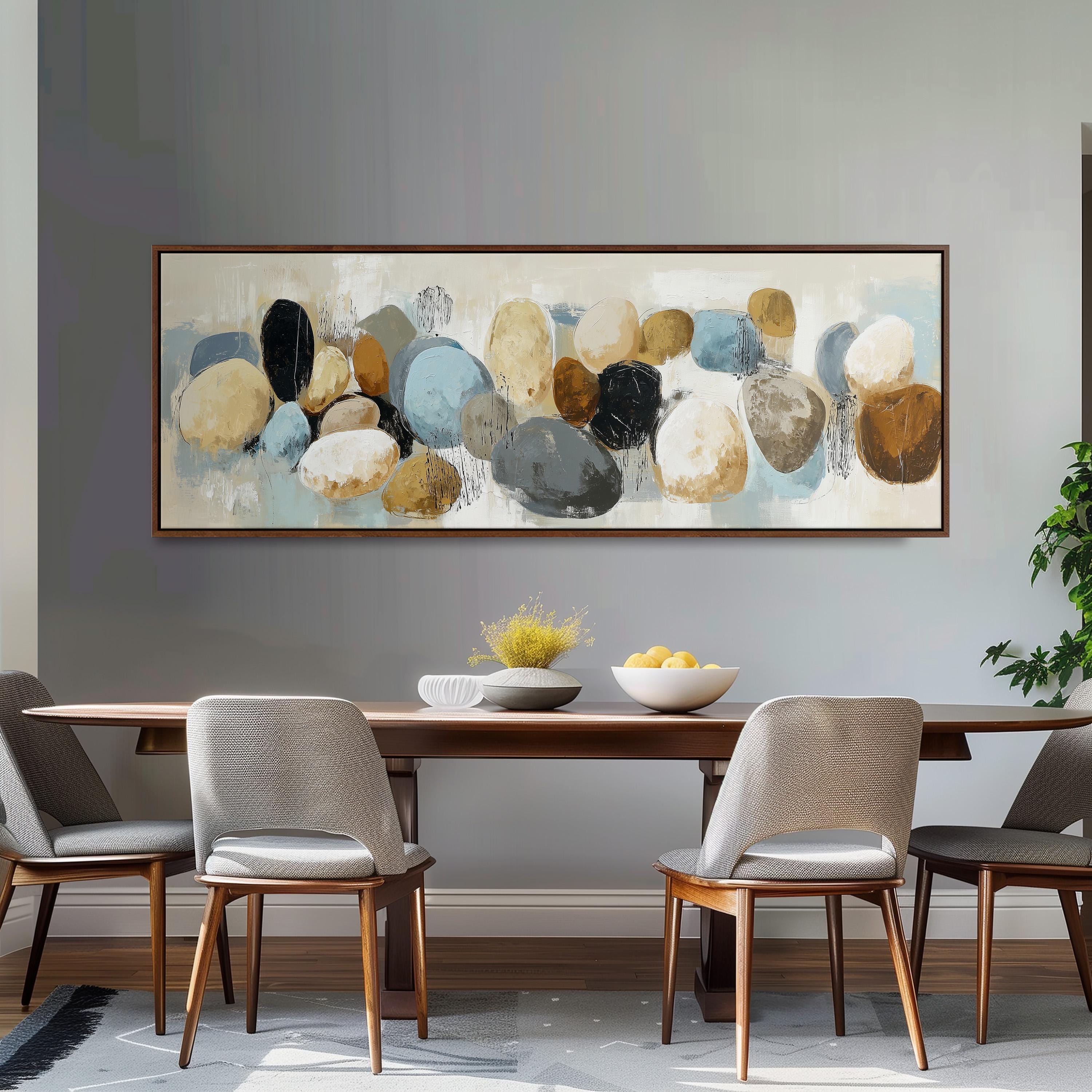 a dining room with a large painting of various colored rocks hanging on the wall above a wooden dining table with four chairs. The table is set with a bowl of fruit and a vase of flowers, creating a cozy and inviting atmosphere.