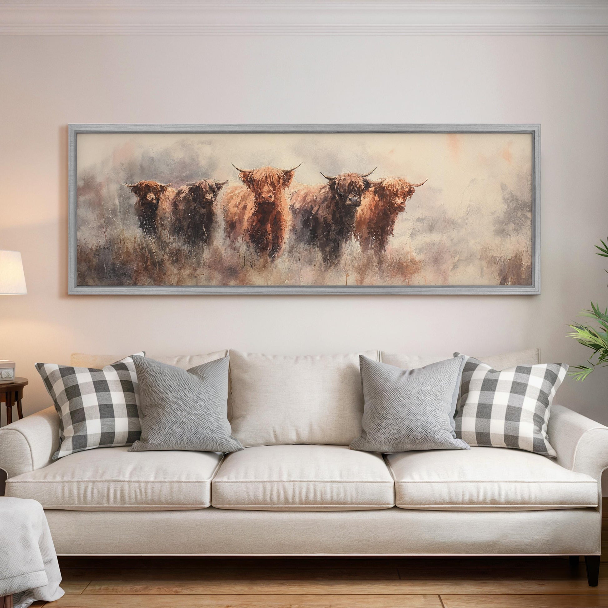 a large painting of four yaks hanging on a wall above a white couch with gray and white plaid throw pillows.
