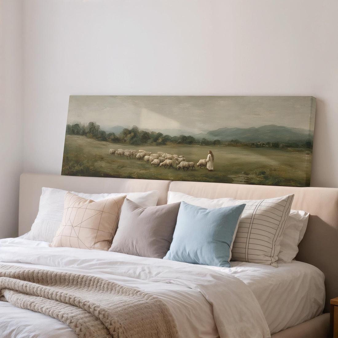 a large painting of a pastoral scene with a woman herding sheep in a grassy field, hanging on a wall above a brown sofa.