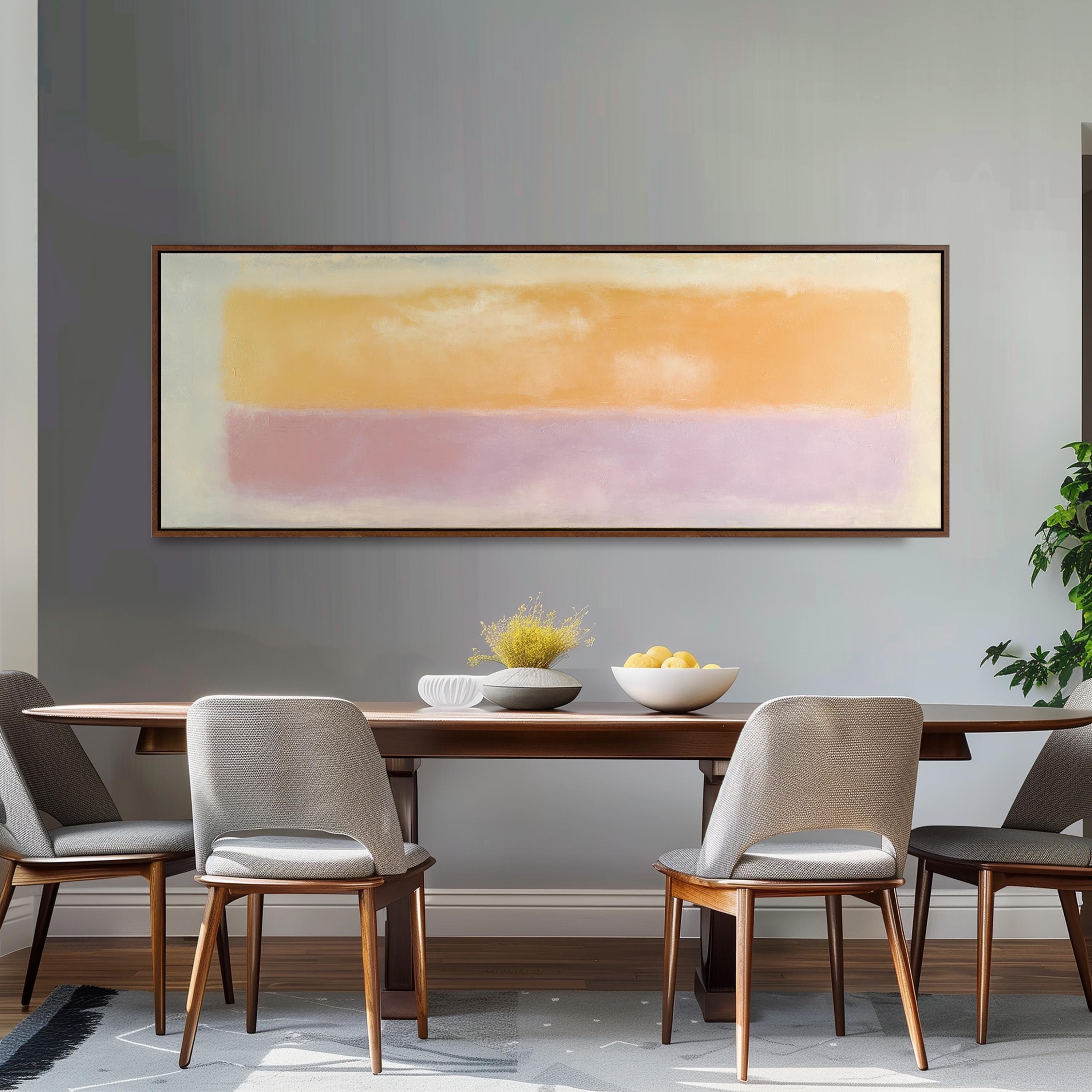 a dining room with a wooden table and four chairs. Above the table, there is a large painting or artwork hanging on the wall. The table is set with a bowl of fruit and a vase of flowers, creating a welcoming and elegant atmosphere.
