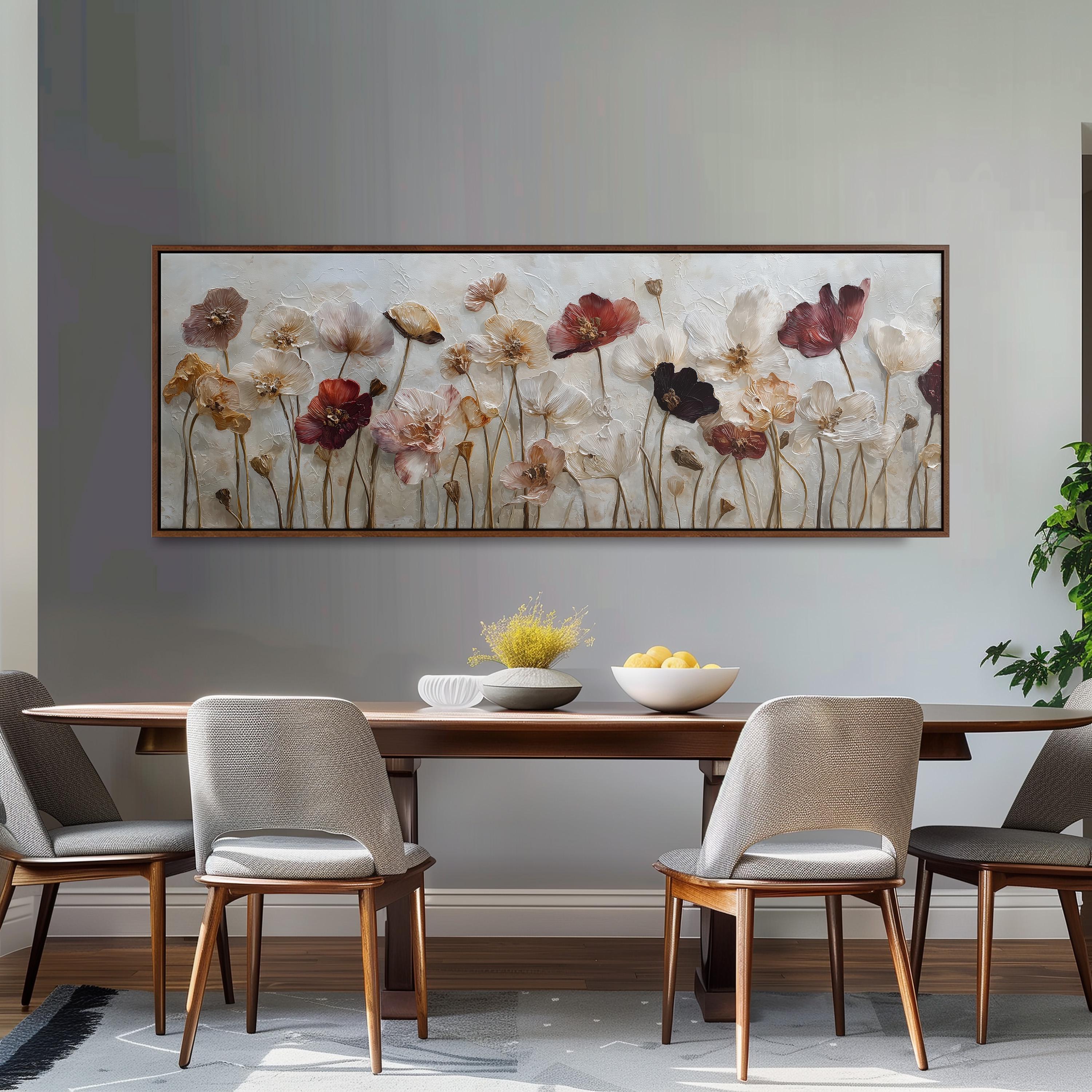 a dining room with a wooden table and four chairs. Above the table, there is a large painting of flowers hanging on the wall. The table is set with a bowl of fruit and a vase of flowers, creating a cozy and inviting atmosphere.