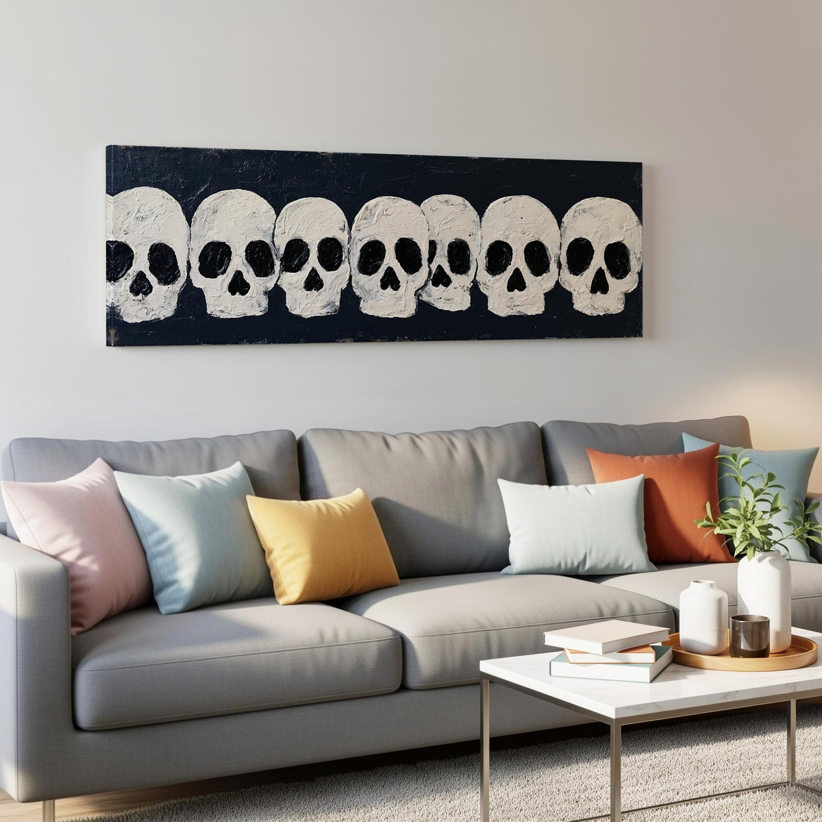 Row of white skulls on navy panoramic canvas print above a grey sofa in a living room
