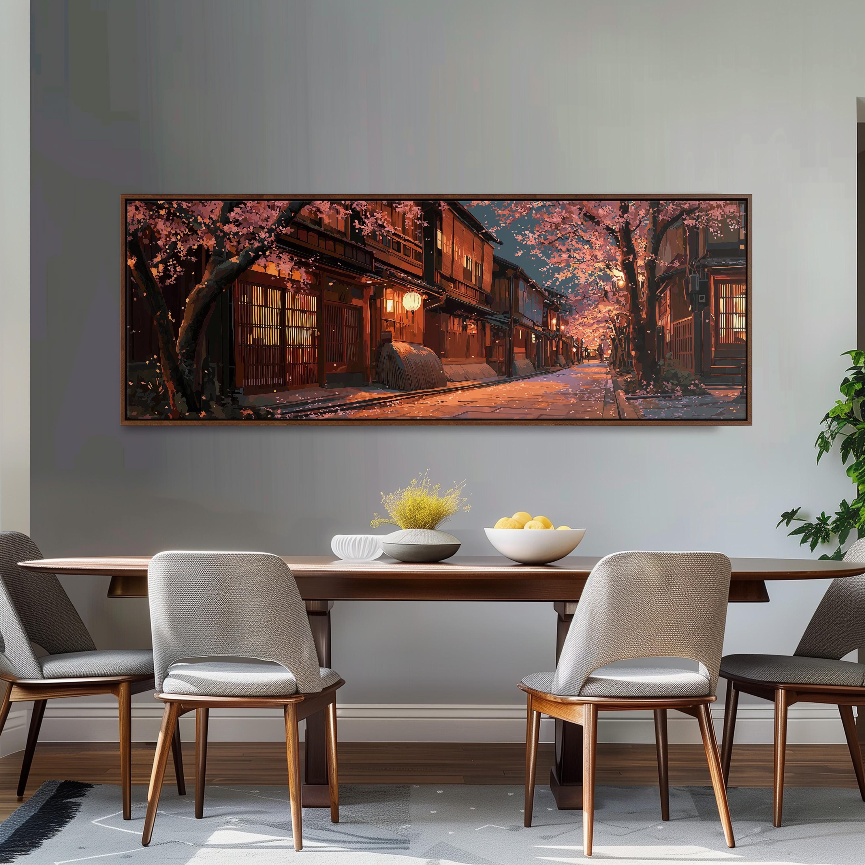 a large, framed painting of a serene street scene with cherry blossoms and a warm, glowing building at the end of the street. The painting is hung on a wall above a wooden dining table with four chairs. The table is set with a bowl of fruit and a vase of flowers, creating a cozy and inviting atmosphere.