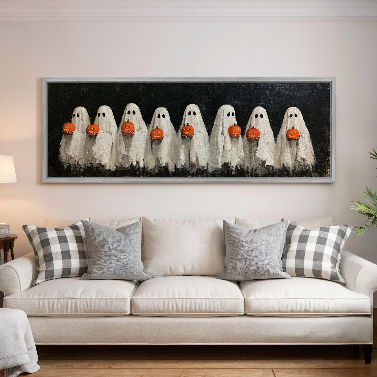 Crowd of huddled ghosts with pumpkins panoramic canvas print above a white sofa in a bright living room