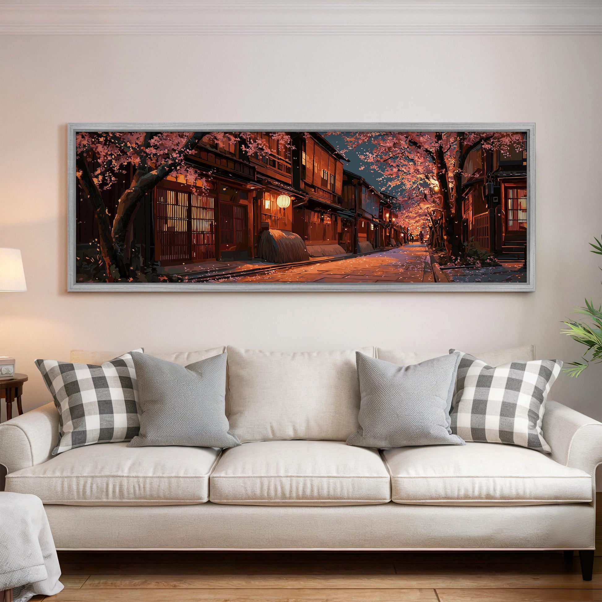 A large framed painting depicting a serene street scene with cherry blossom trees and traditional Japanese buildings is displayed on the wall above a white sofa in a living room.
