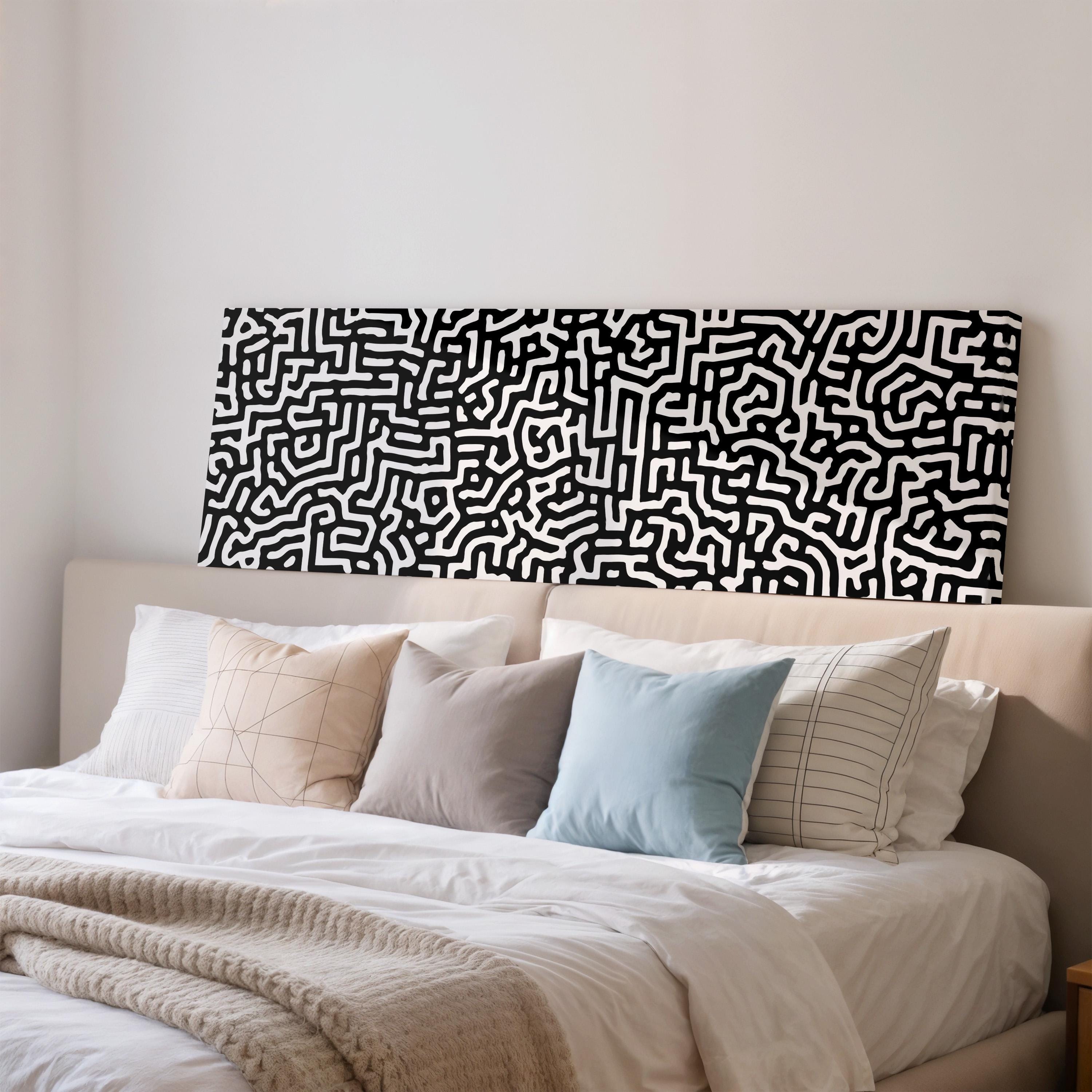 a bed with a black and white abstract pattern on the headboard, and the bed is covered with a white comforter and pillows.