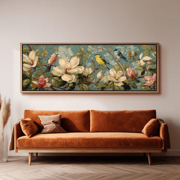 a large, framed painting of a floral scene with birds perched on branches, hanging on a wall above a brown sofa.