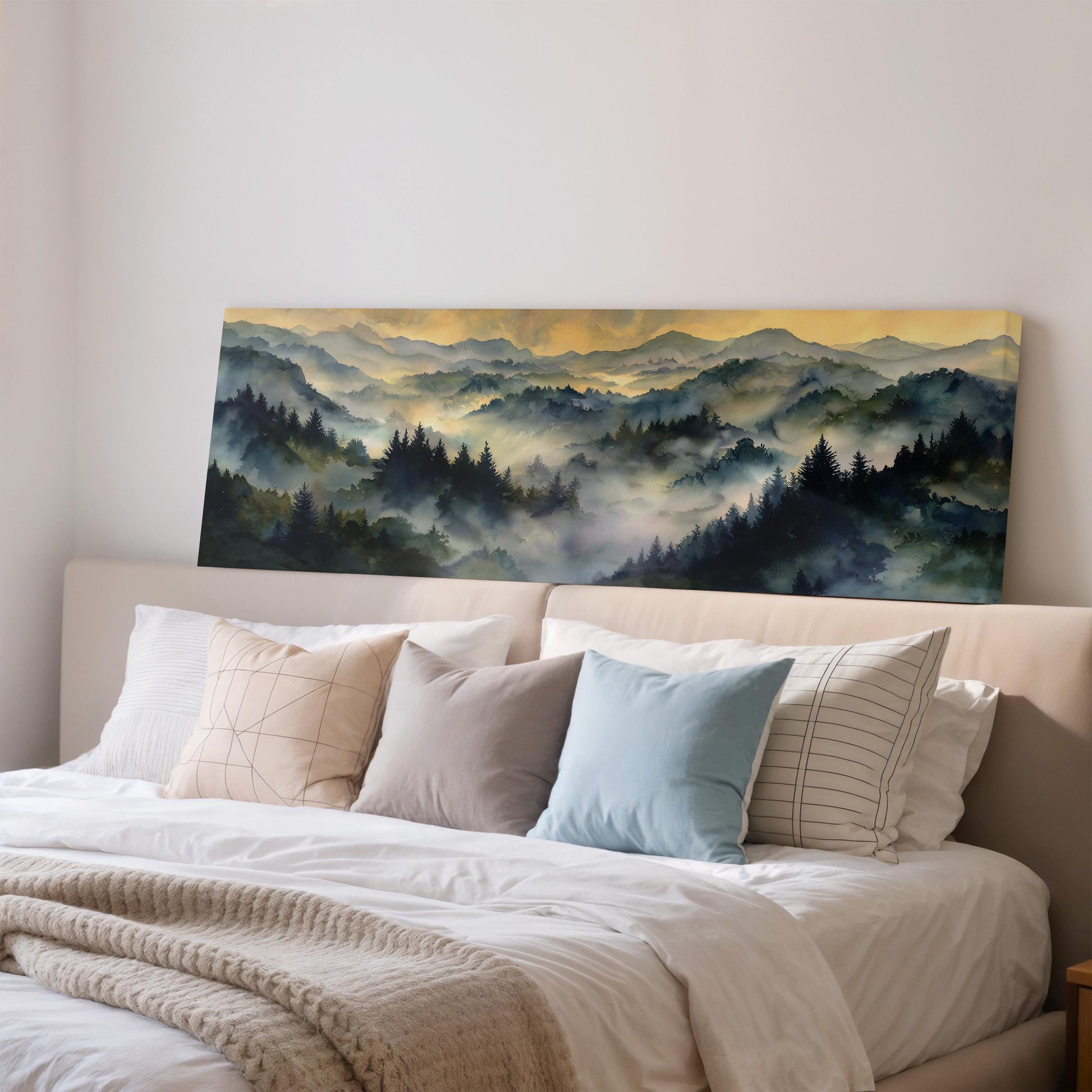 a large painting of a mountain landscape hanging on a wall above a bed with white bedding and various pillows.