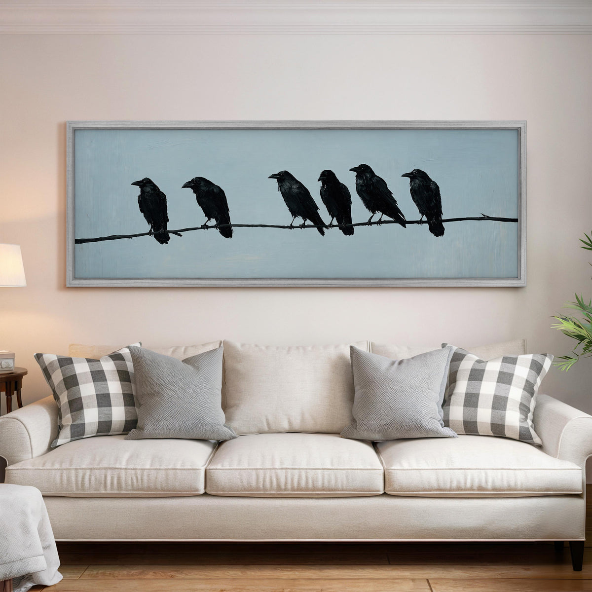 Ravens spaced along a wire panoramic canvas print above a white sofa in a bright living room