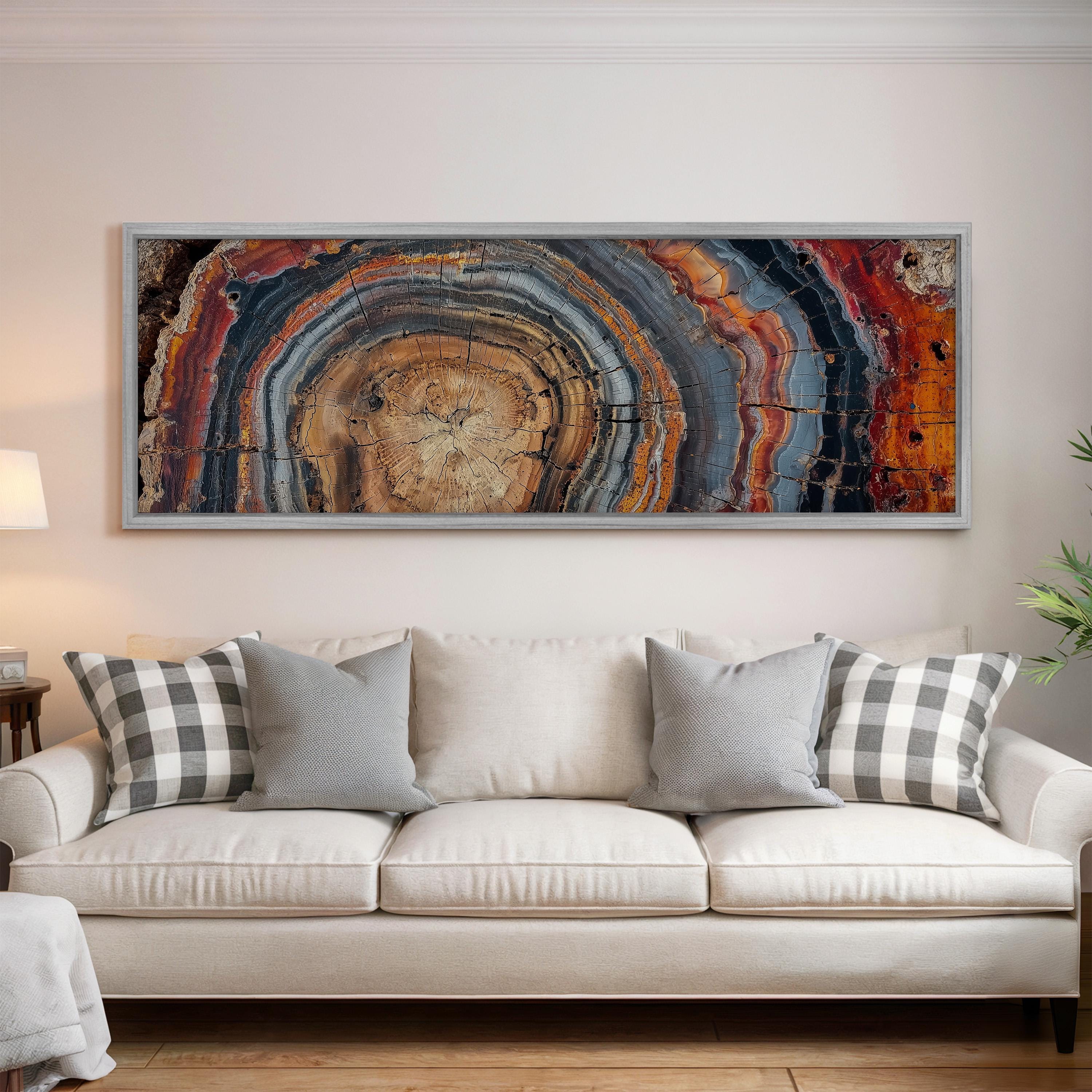 a large, colorful abstract painting hanging on a wall above a white couch with gray and white plaid throw pillows.