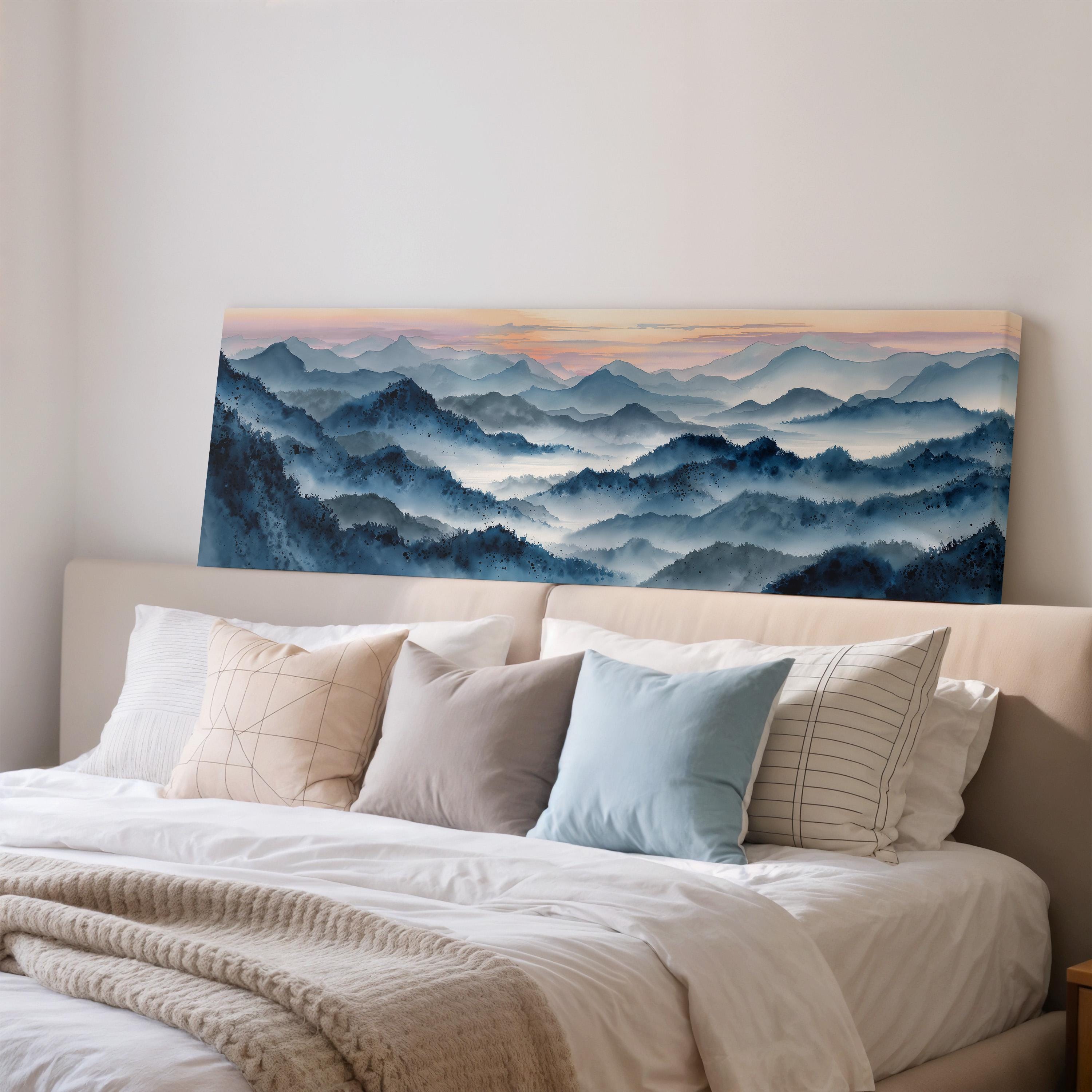 a large painting of a mountain landscape hanging on a wall above a bed with white bedding and pillows.