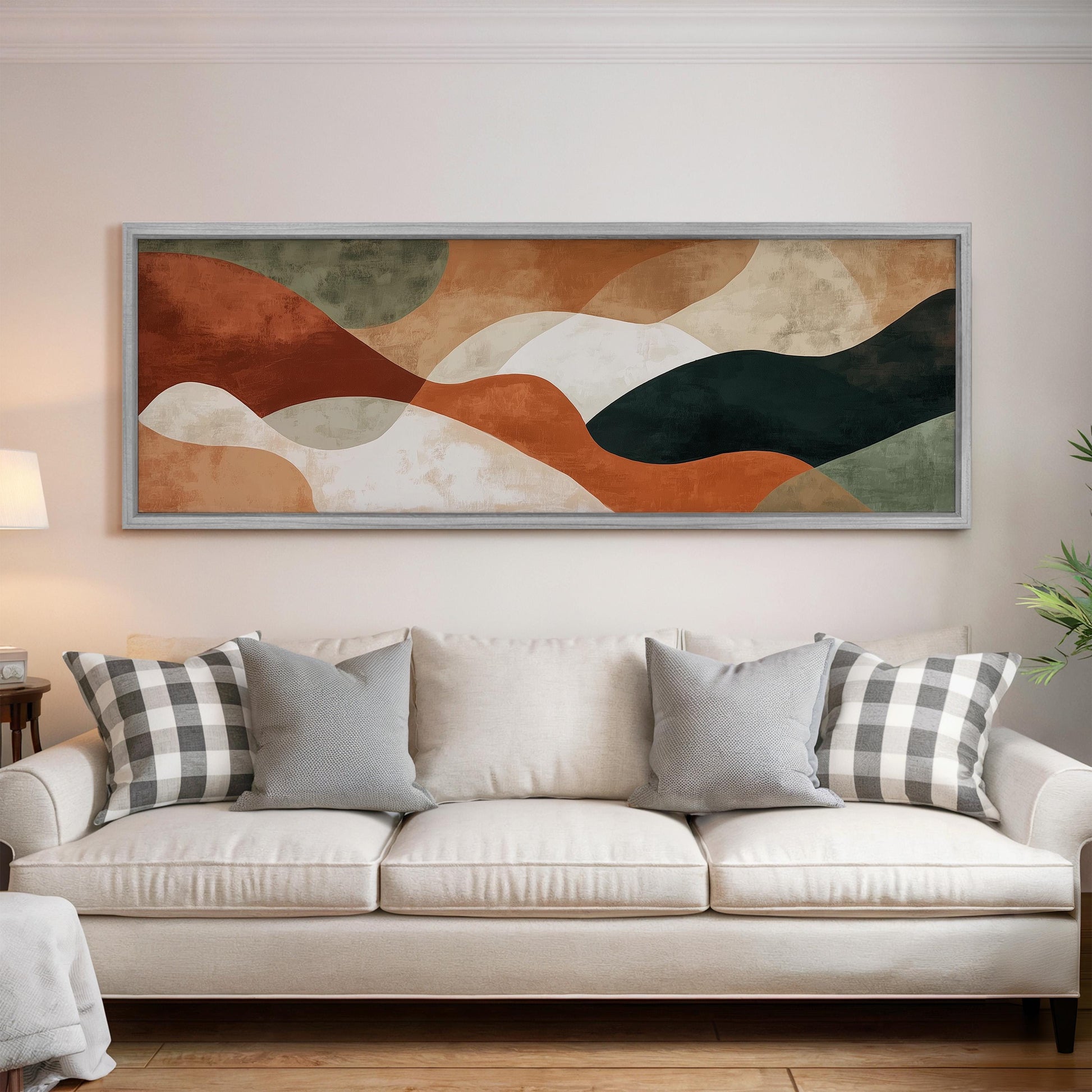 a large abstract painting hanging on a wall above a white sofa with gray and white plaid throw pillows.