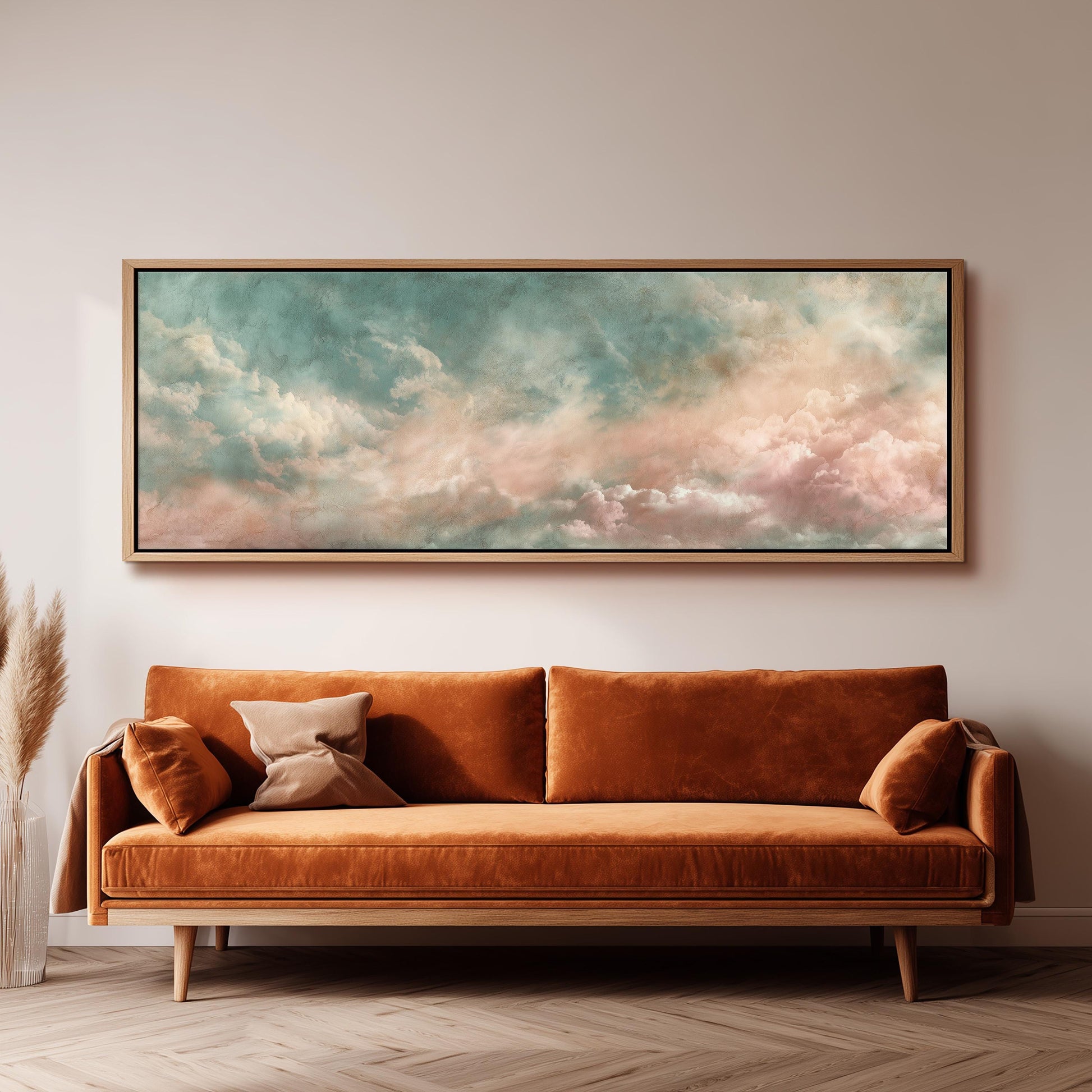 a large, framed painting of a cloudy sky hanging on a wall above a brown sofa with two pillows.