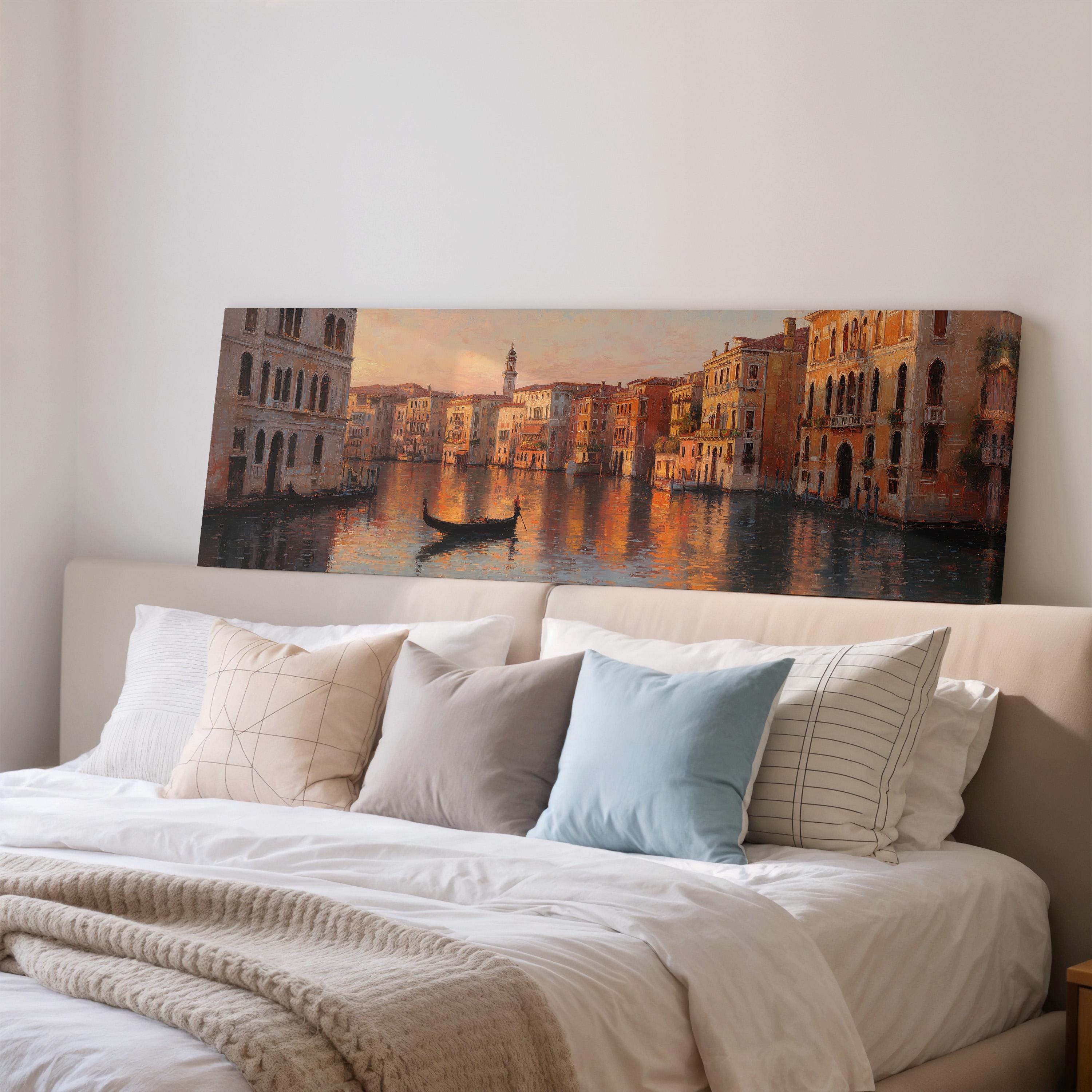a large painting of a cityscape with a gondola on the water, hanging on a wall above a bed with white pillows and a gray blanket.