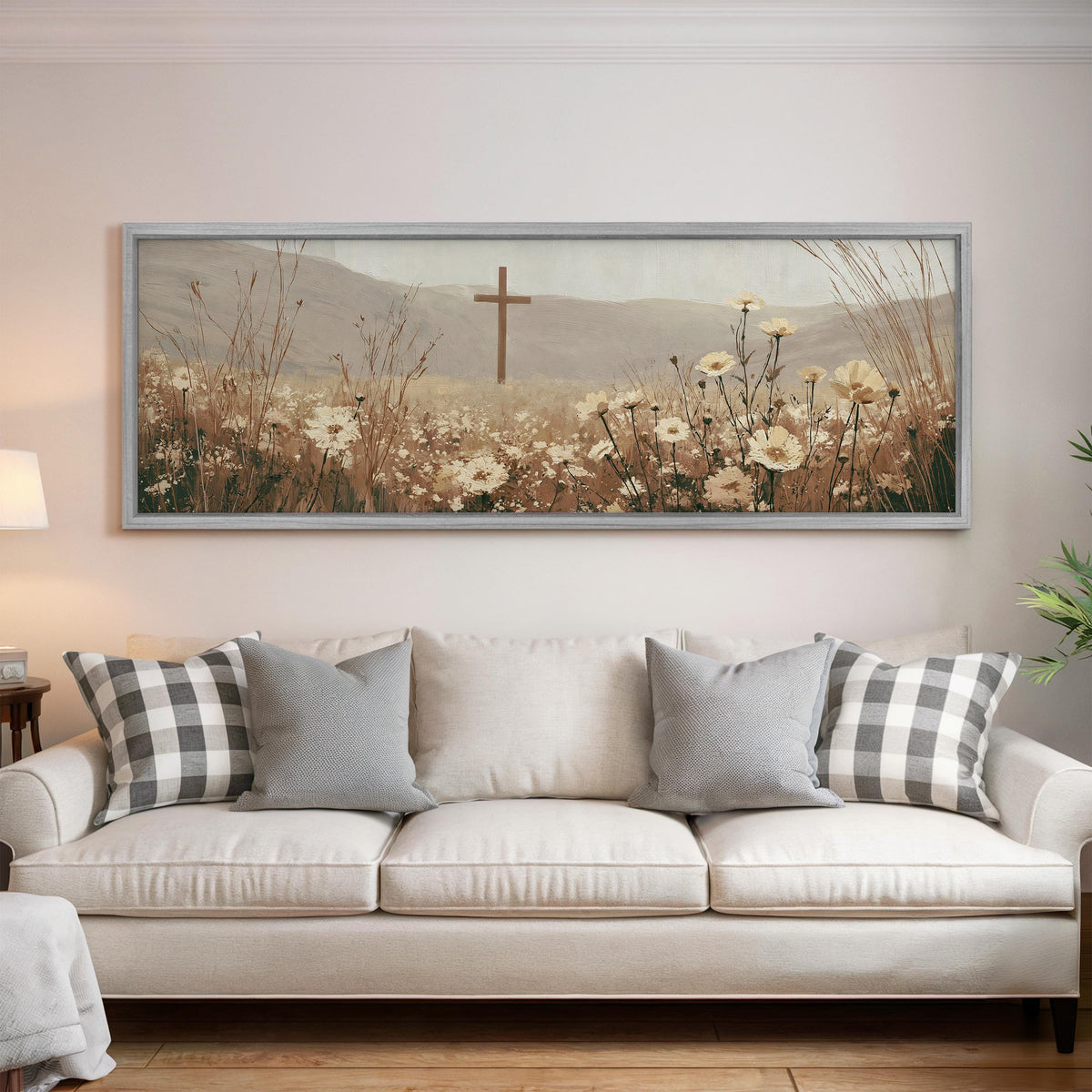 Wooden cross in a cream wildflower field panoramic canvas print above a white sofa in a bright living room