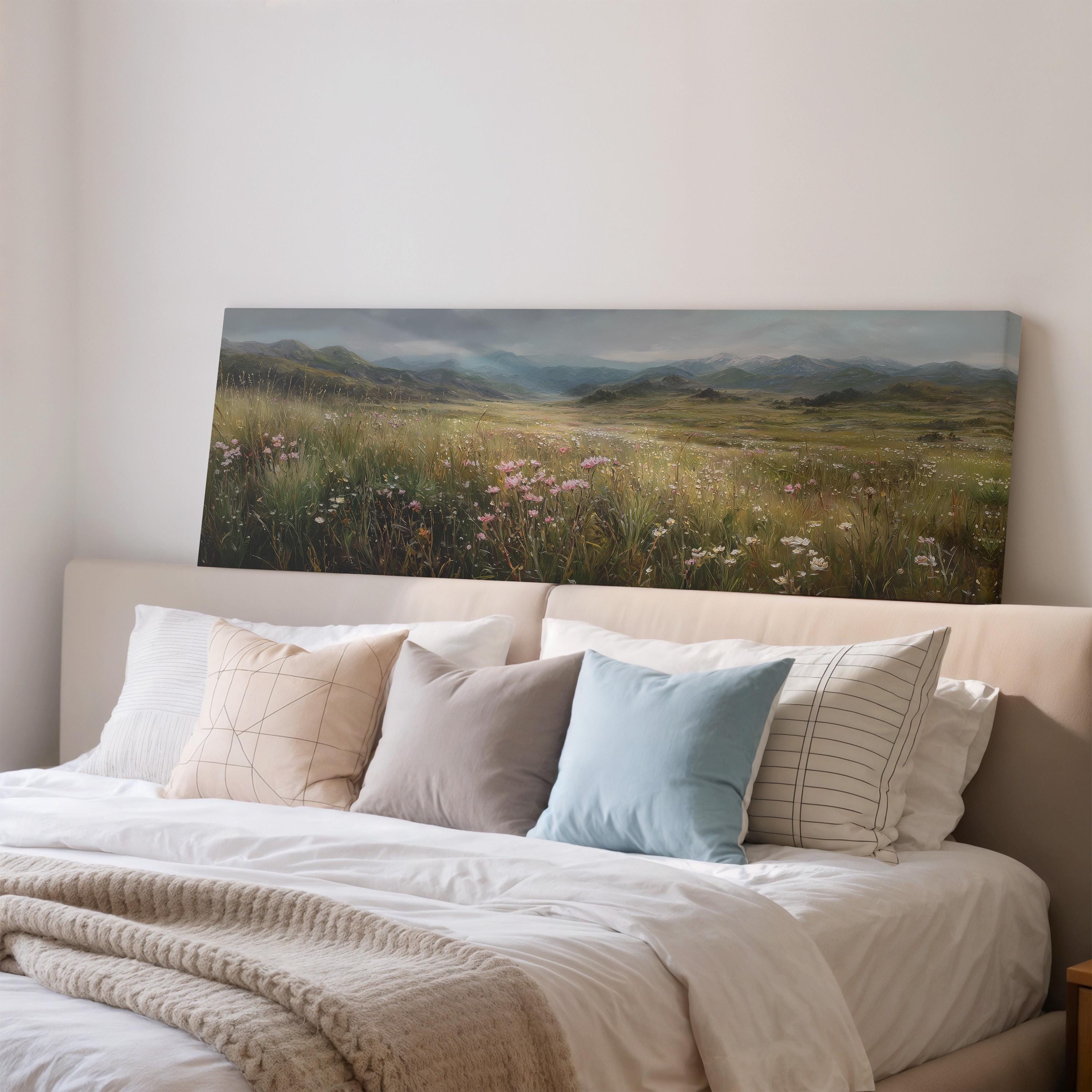 a large landscape painting hanging on a wall above a bed with white bedding and pillows.
