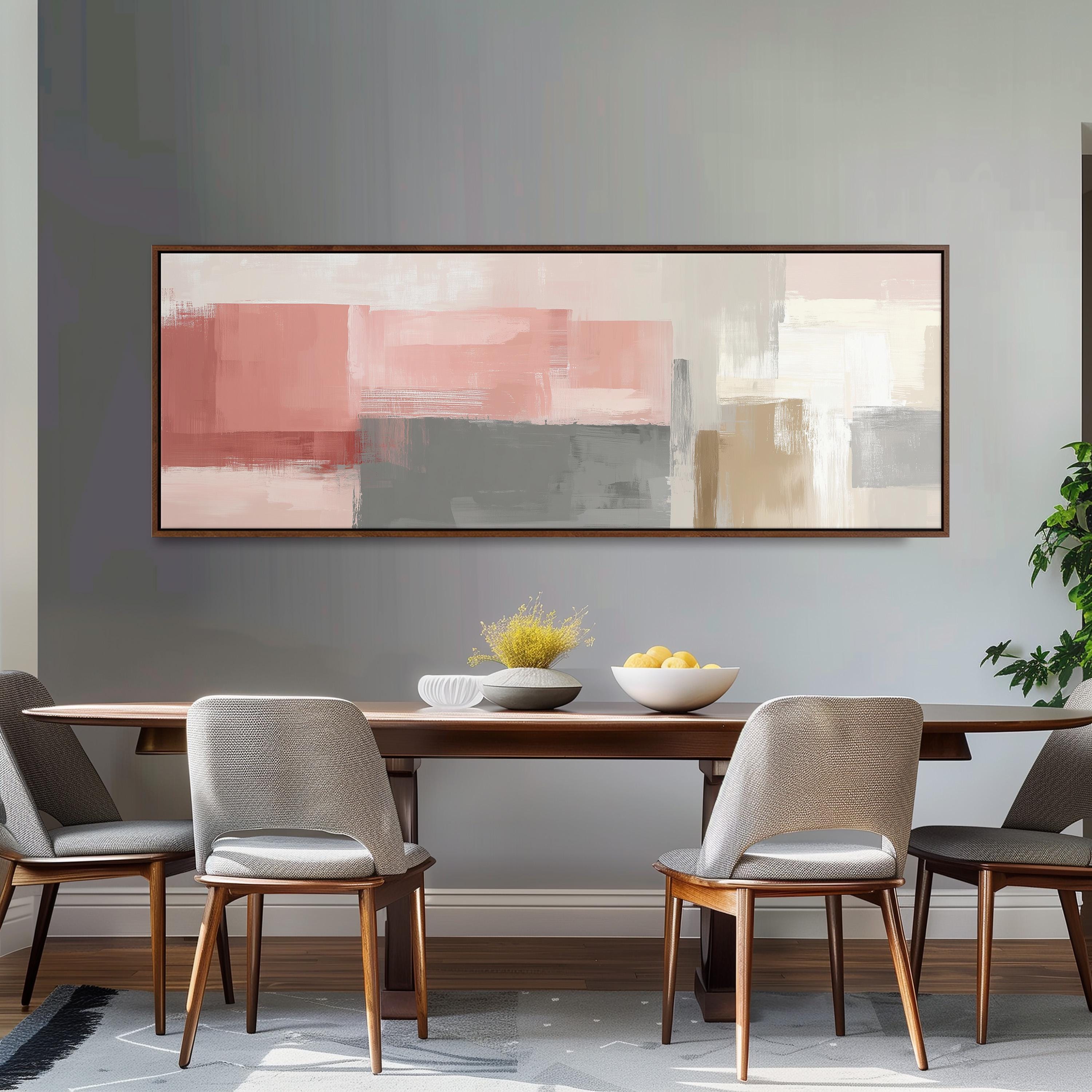 a modern dining room with a wooden table and four gray chairs. Above the table, there is a large abstract painting in shades of pink and gray. On the table, there is a bowl of fruit and a vase of flowers.