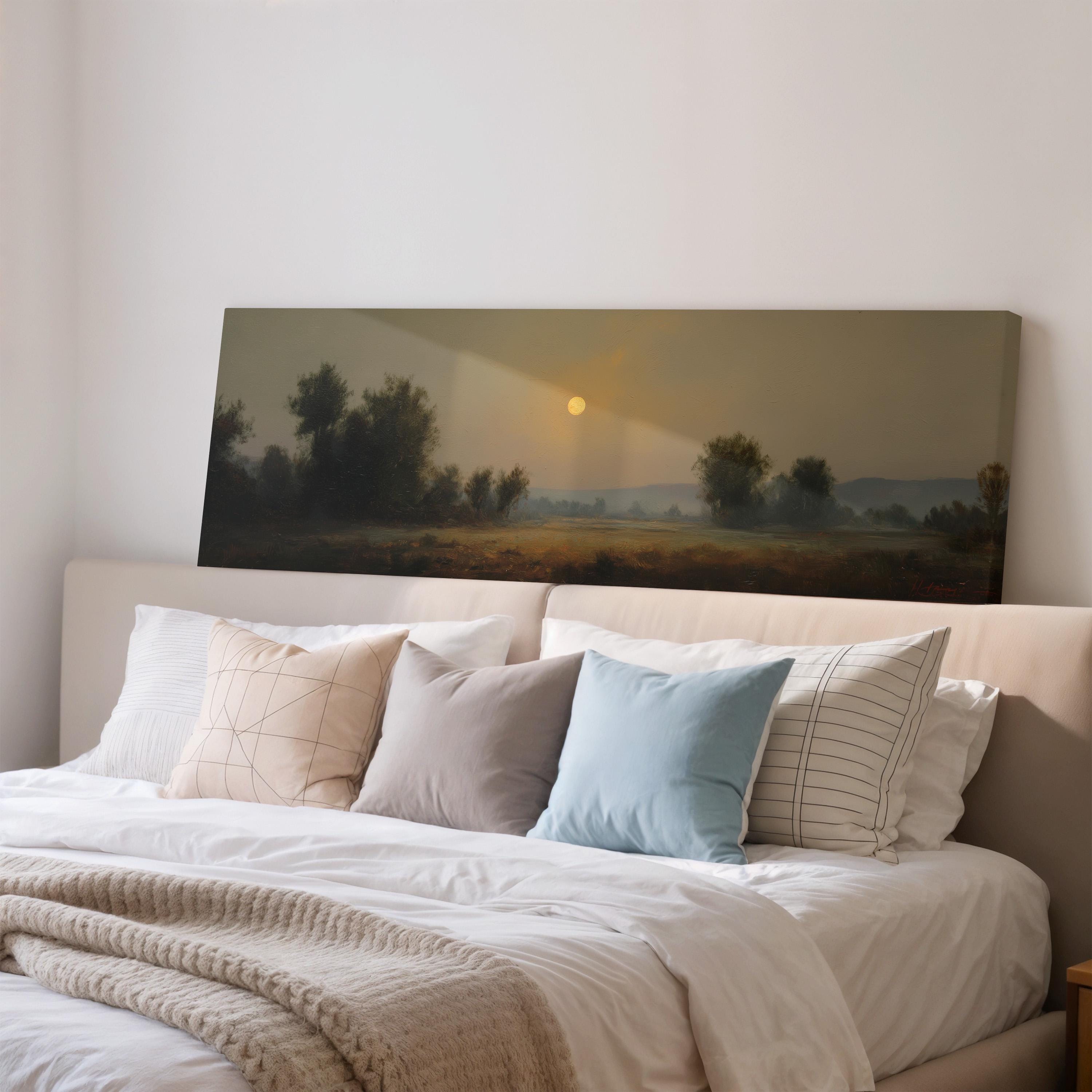 a large painting of a landscape with a sunset over a field, hanging above a bed with white pillows and a gray blanket.