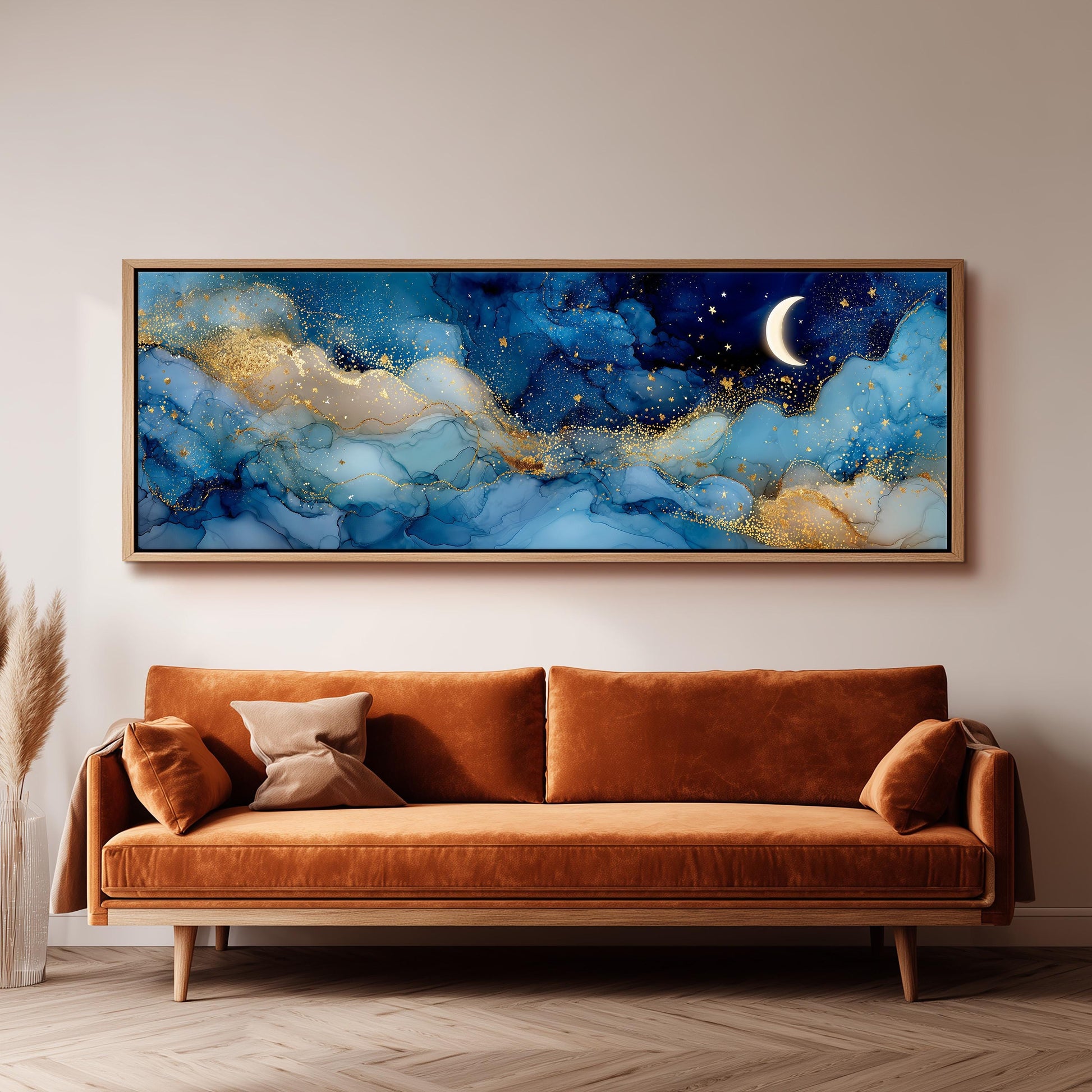 a large, framed painting of a night sky with a crescent moon and stars, hanging on a wall above a brown sofa.