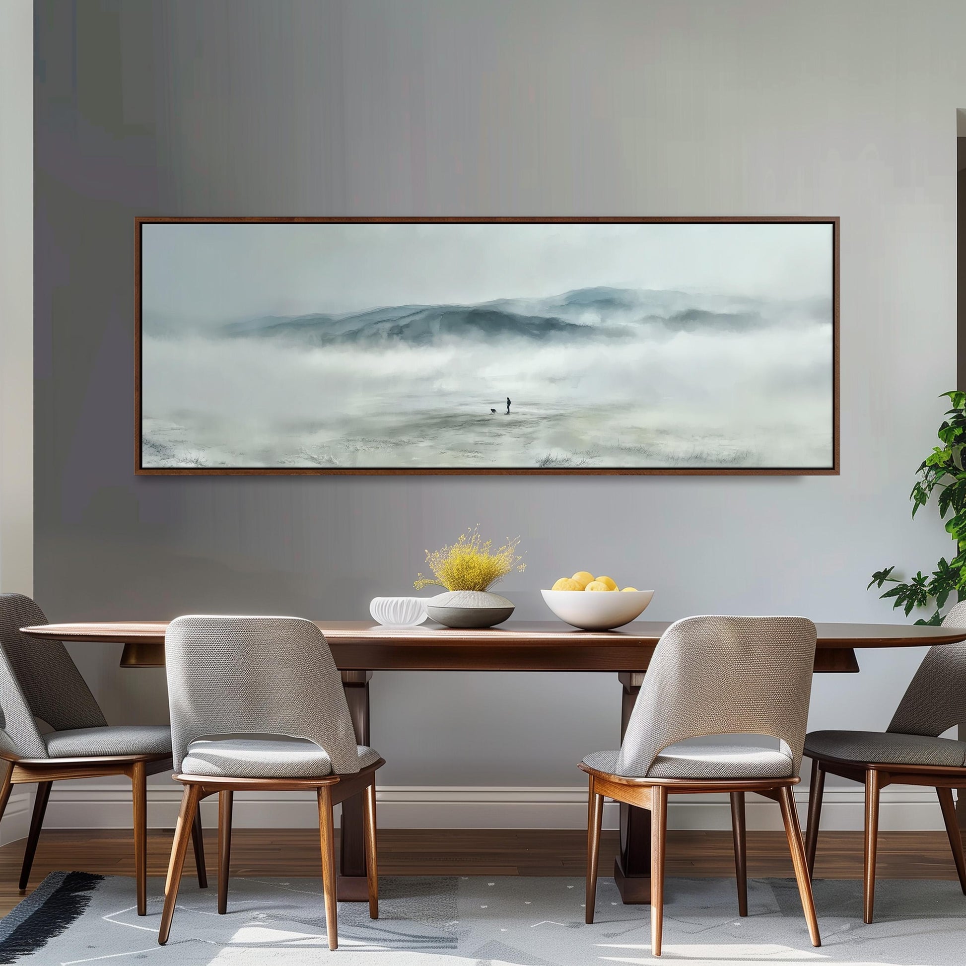 a dining room with a large painting of a misty mountain landscape hanging on the wall above a wooden dining table with four chairs. The table is set with a bowl of fruit and a vase of flowers, creating a cozy and inviting atmosphere.