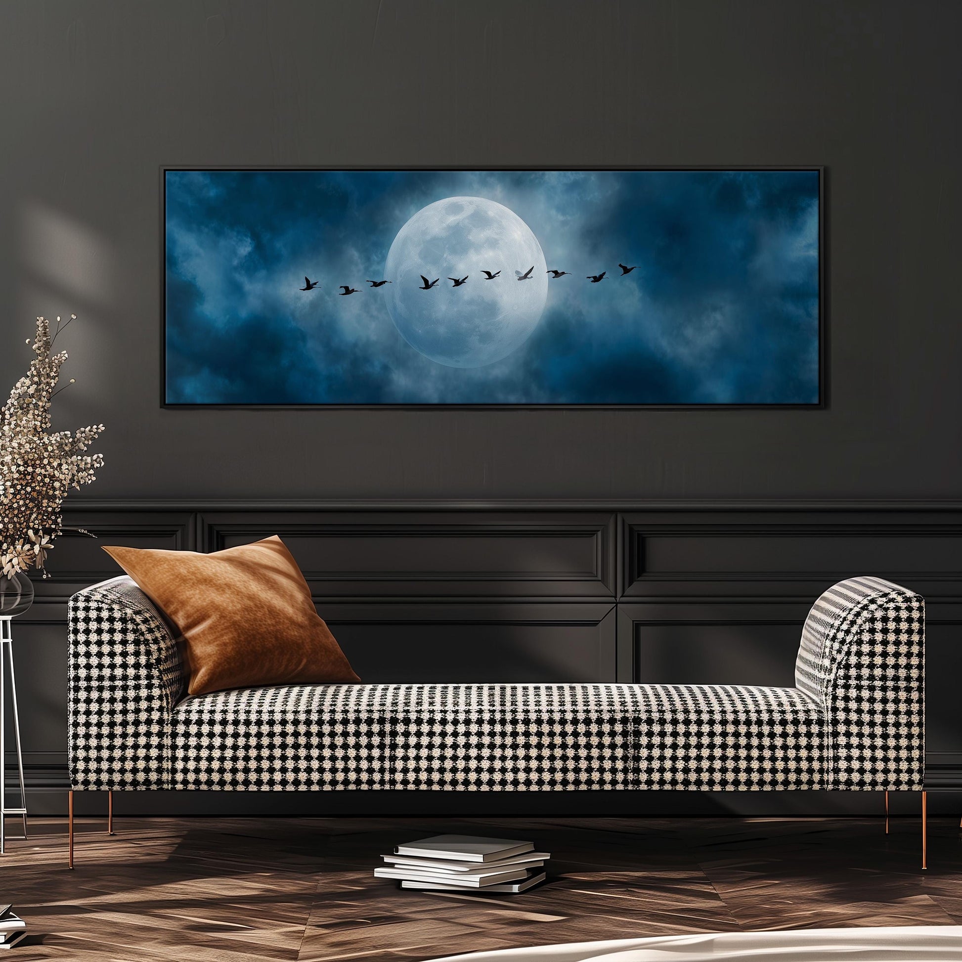 a large black and white checkered sofa with a brown throw pillow, positioned in front of a wall with a framed image of a flock of birds flying across a night sky with a full moon.