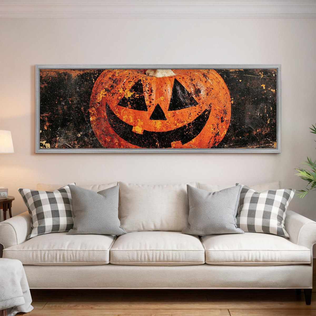 Rustic distressed jack-o'-lantern panoramic canvas print above a white sofa in a bright living room