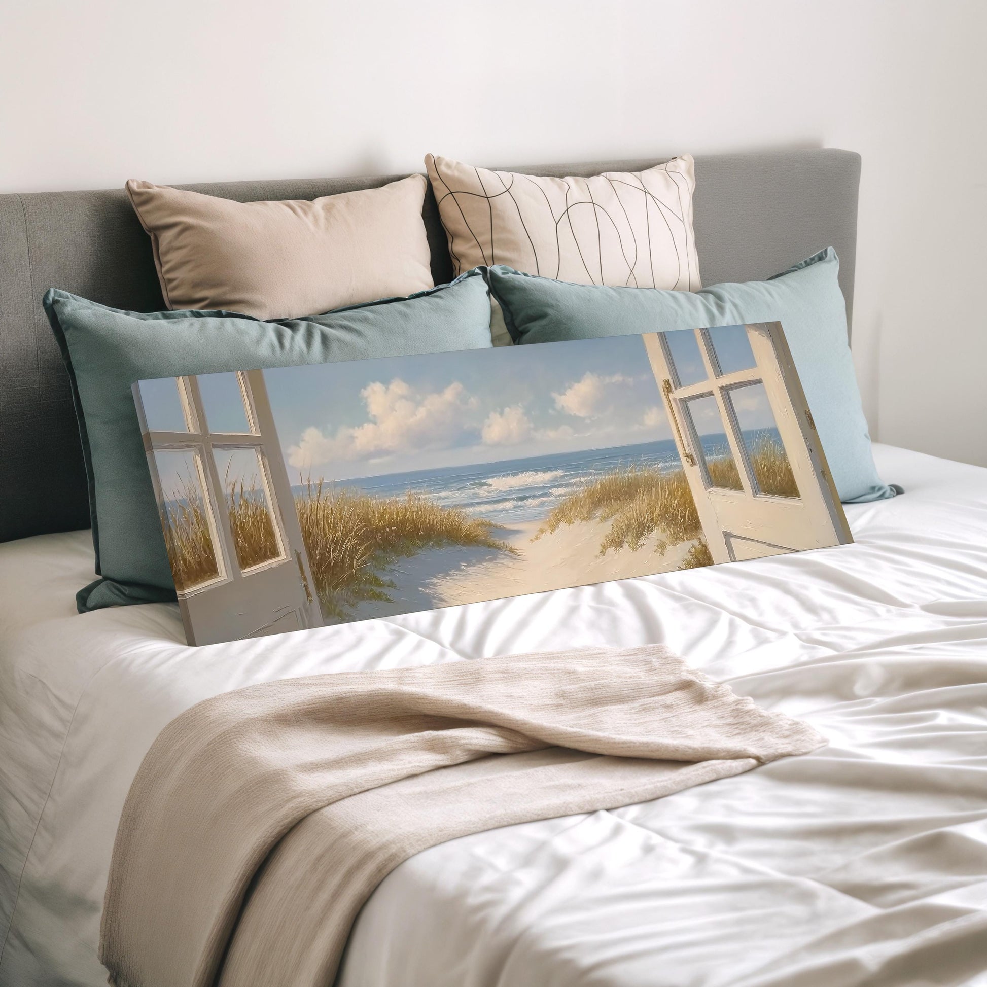 a bedroom with a large painting of a beach scene on the bed, featuring a view of the ocean and a path leading to the beach.