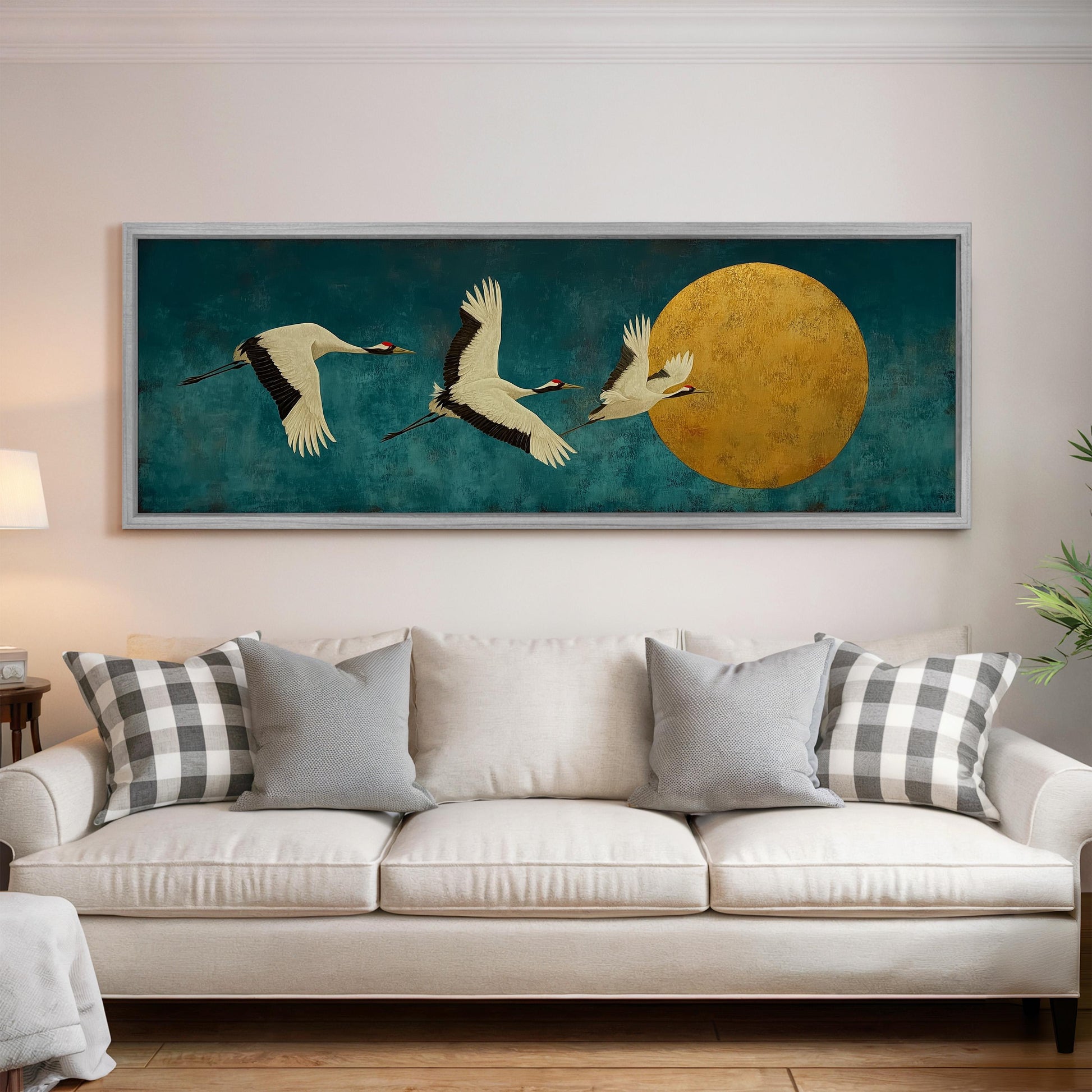 a large painting of three white birds in flight, with a large yellow circle in the background, hanging on a wall above a white couch.