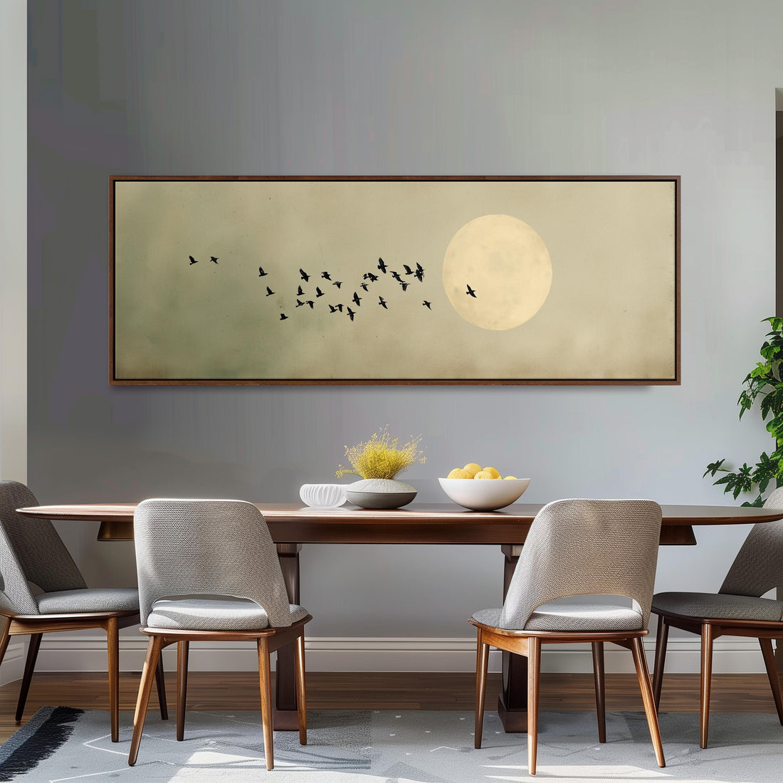 a large framed picture of a flock of birds flying over a moonlit sky, hanging on a wall above a white couch with gray and white plaid throw pillows.