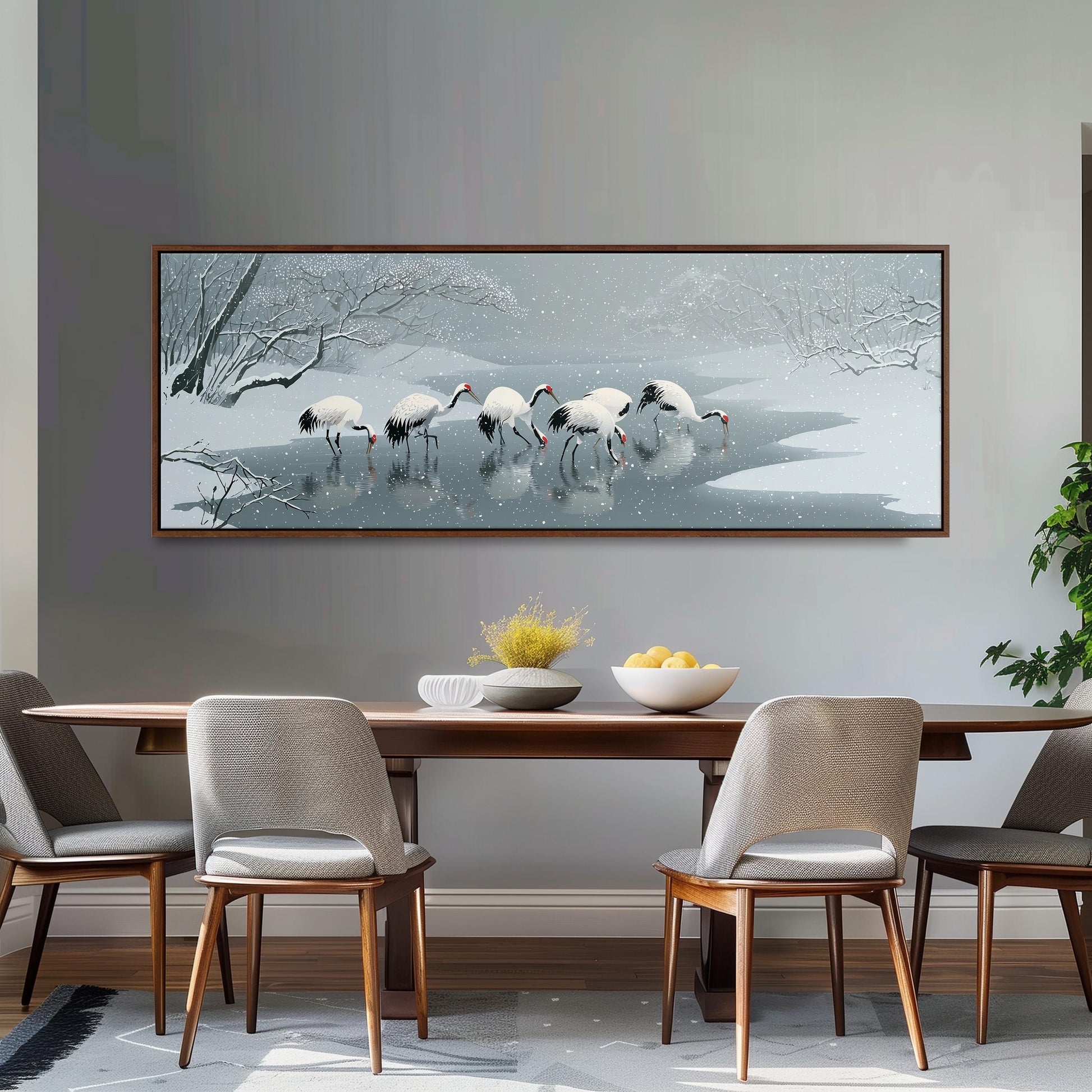 a large painting of a snowy landscape with a group of birds standing in a body of water, surrounded by snow-covered trees. The painting is hung on a wall above a wooden dining table with four chairs.