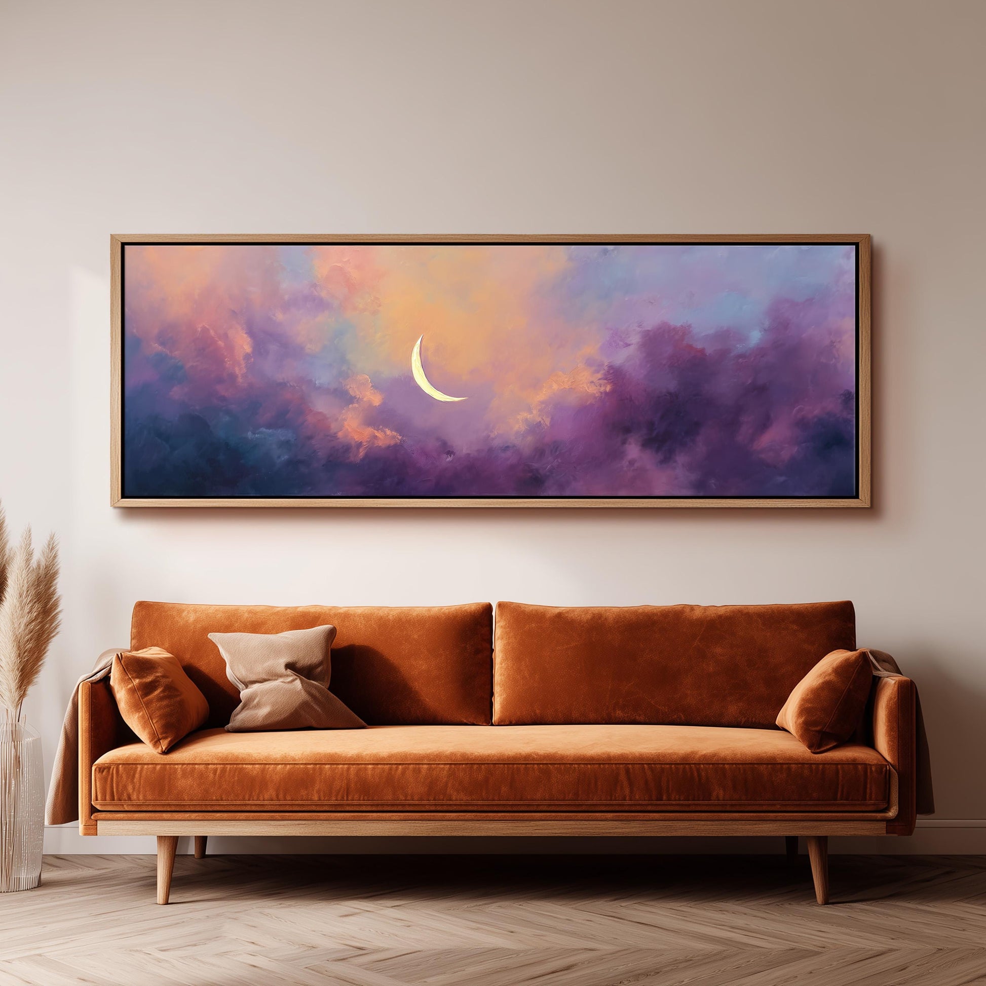 a large, framed painting of a crescent moon set against a colorful, cloudy sky. The painting is hanging on a wall above a brown sofa, creating a cozy and inviting atmosphere in the room.