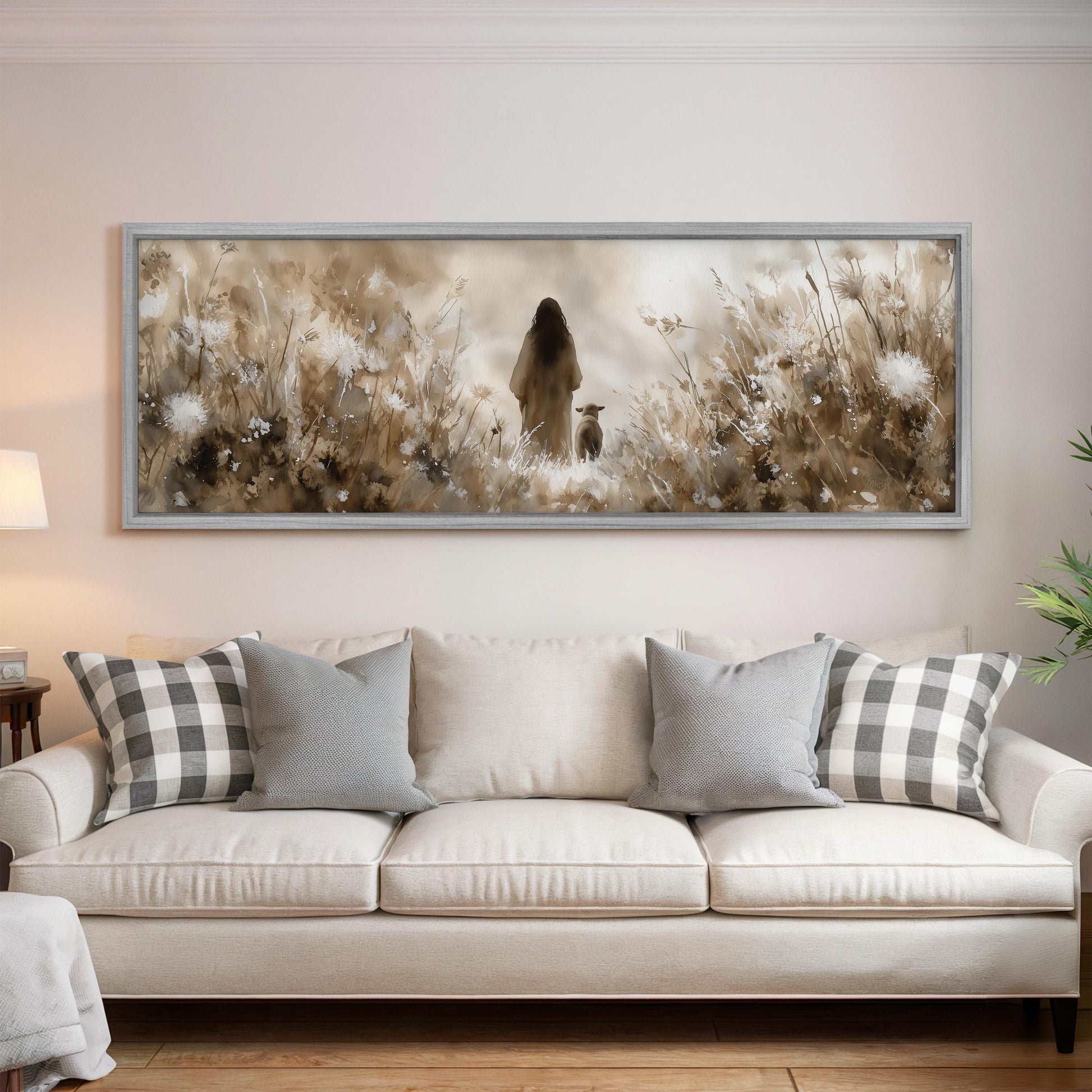 a large, framed painting of a woman standing in a field of flowers, with a dog in the background. The painting is hanging on a wall above a white couch with gray and white plaid throw pillows.