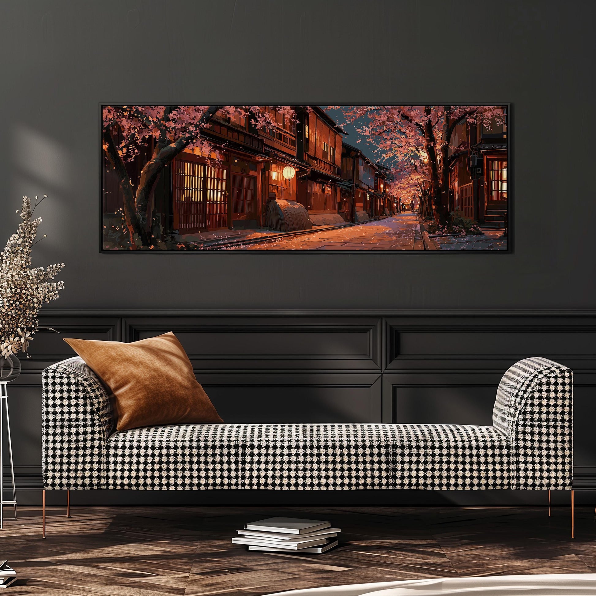a cozy living room with a black and white checkered sofa, a stack of books, and a large framed painting depicting a serene street scene with cherry blossoms in full bloom.