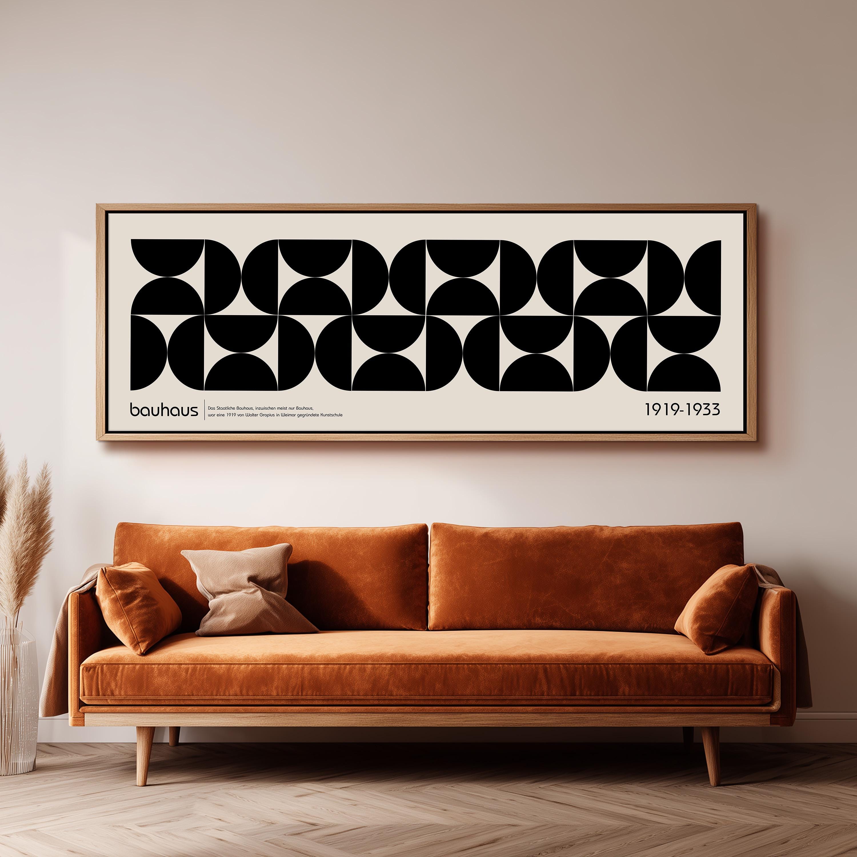 a large black and white abstract art piece hanging on a wall above a brown sofa with a pillow.