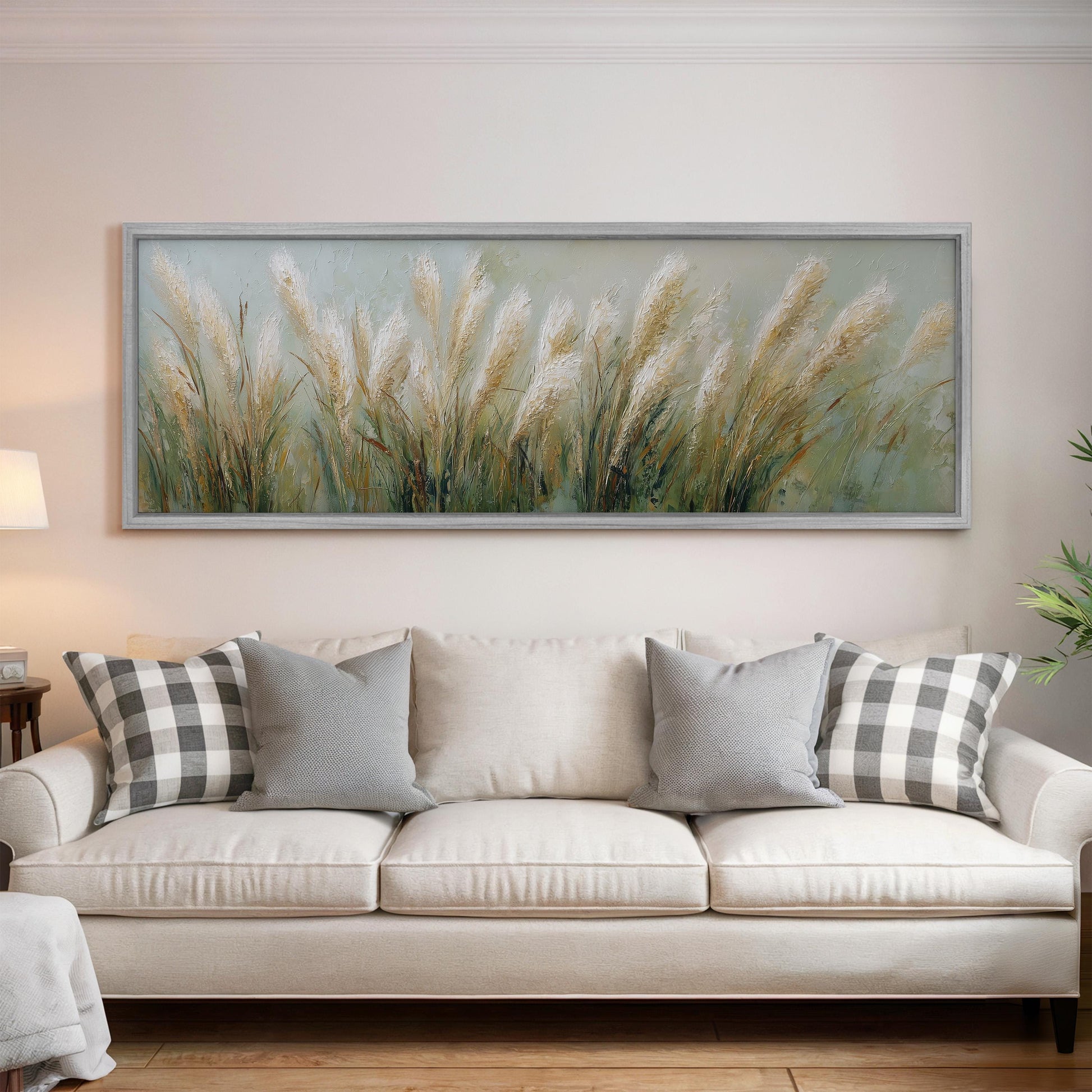a large painting of tall grass hanging on a wall above a white sofa with gray and white patterned pillows.