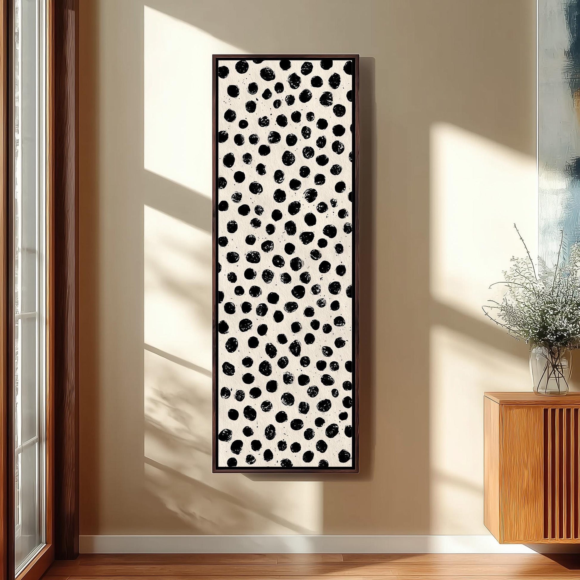 a wall with a large black and white abstract painting hanging on it. The painting has a pattern of black dots on a white background, creating a striking contrast. The painting is framed and mounted on the wall, adding a modern and artistic touch to the room.