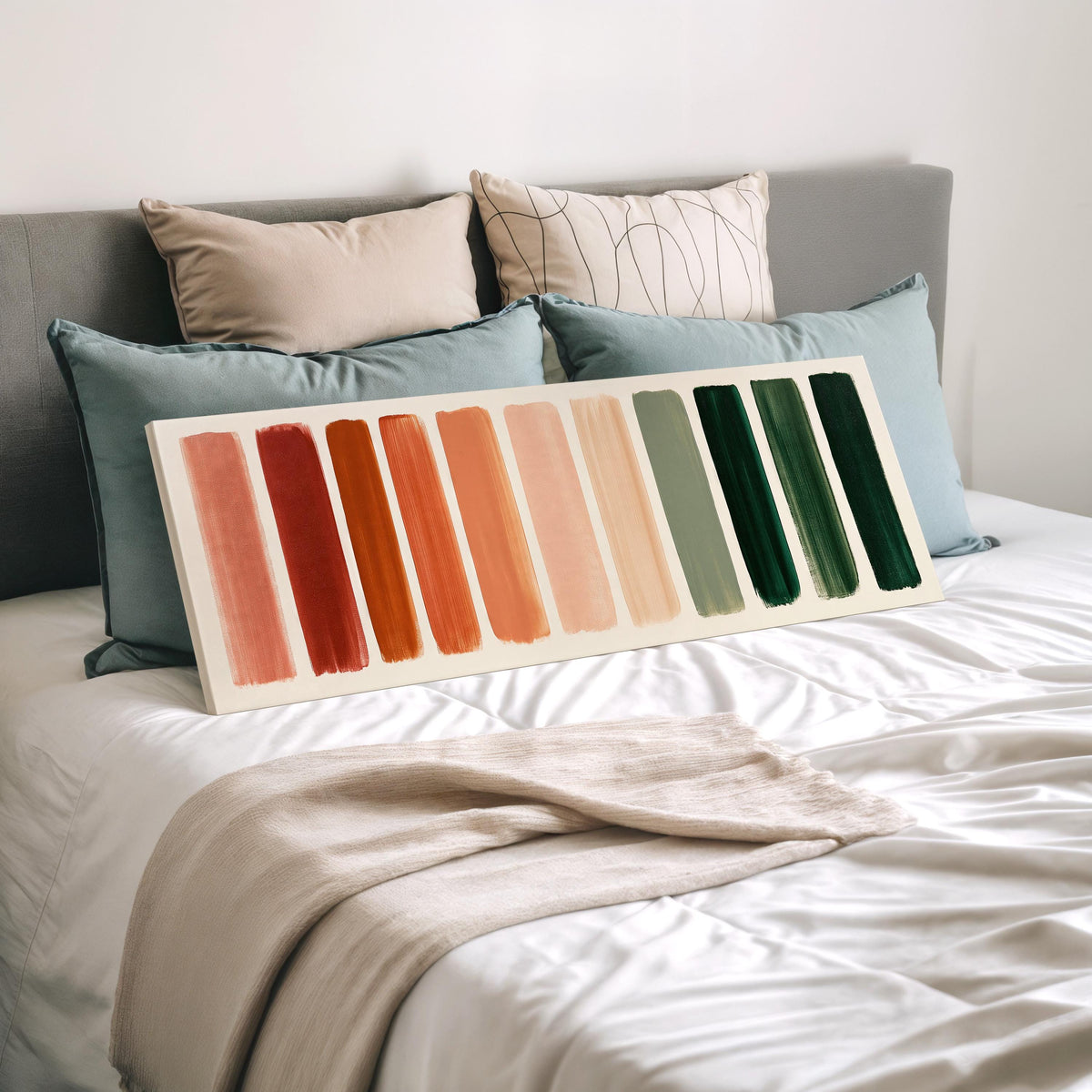 Brushed swatches from terracotta to forest green wide panoramic canvas print laid on a bed to show its size