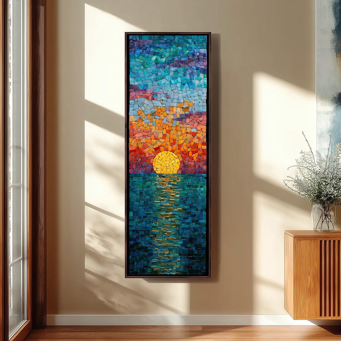 a large, colorful mosaic artwork depicting a sunset over a body of water, hanging on a wall in a room with a wooden cabinet and a vase of flowers.