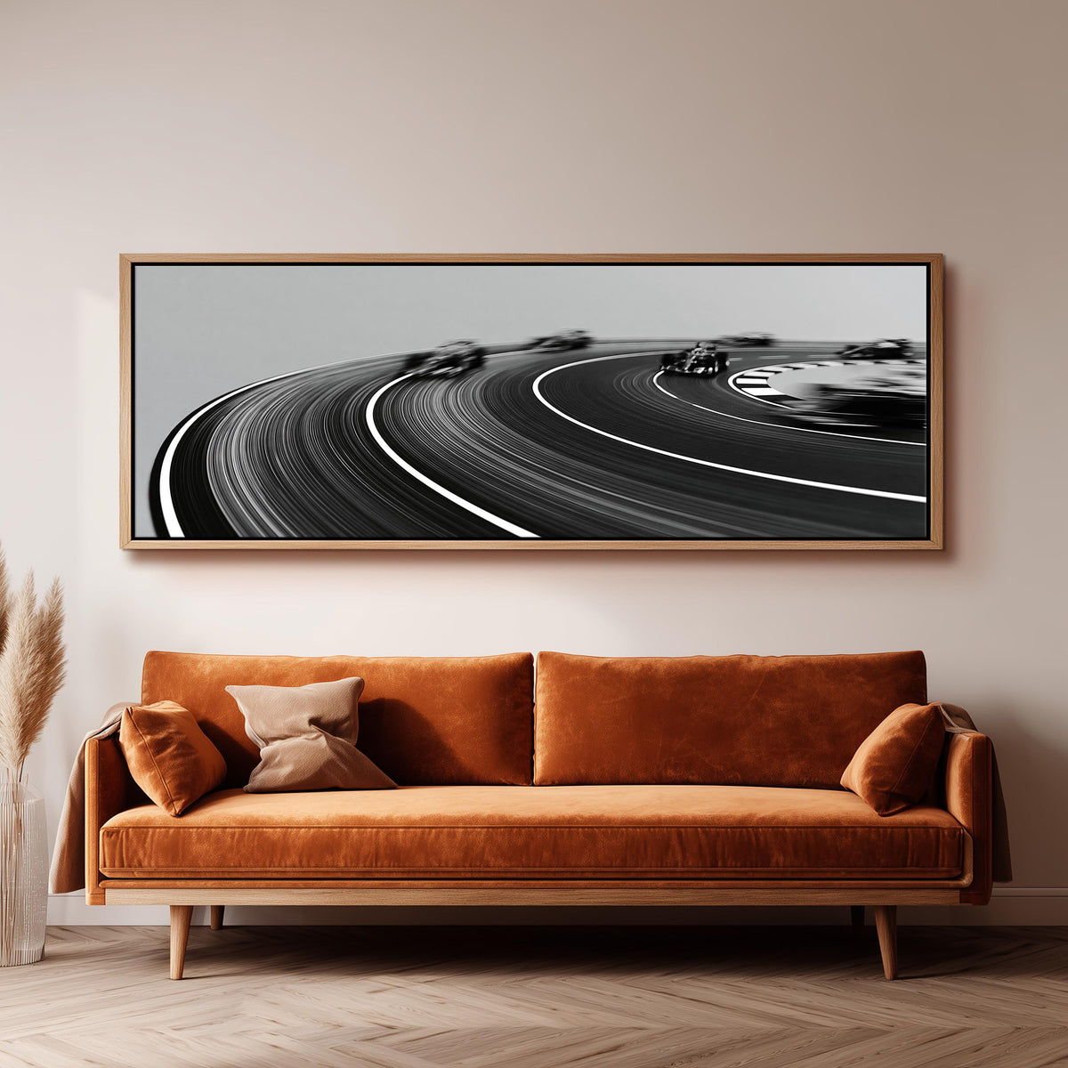 Race cars sweeping around a curve in black and white wide panoramic canvas print above a bench in a dark living room