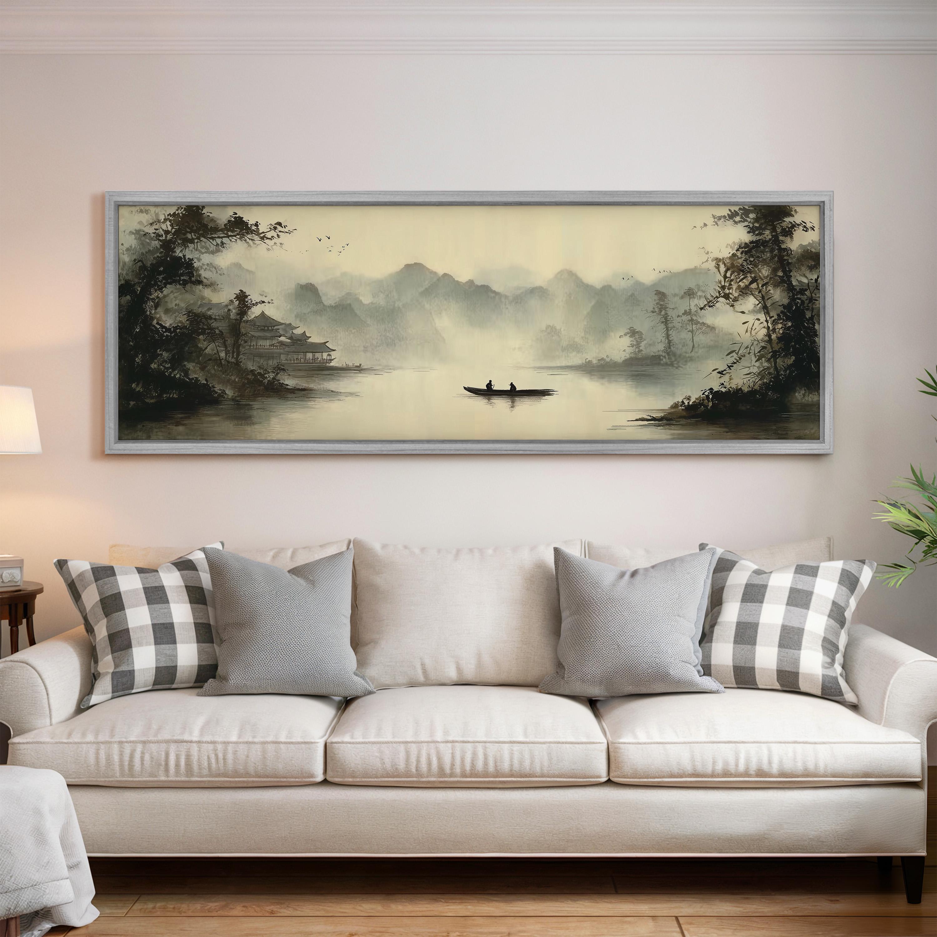 a large painting of a serene landscape with a boat on a lake, hanging on a wall above a white sofa with gray and white patterned pillows.