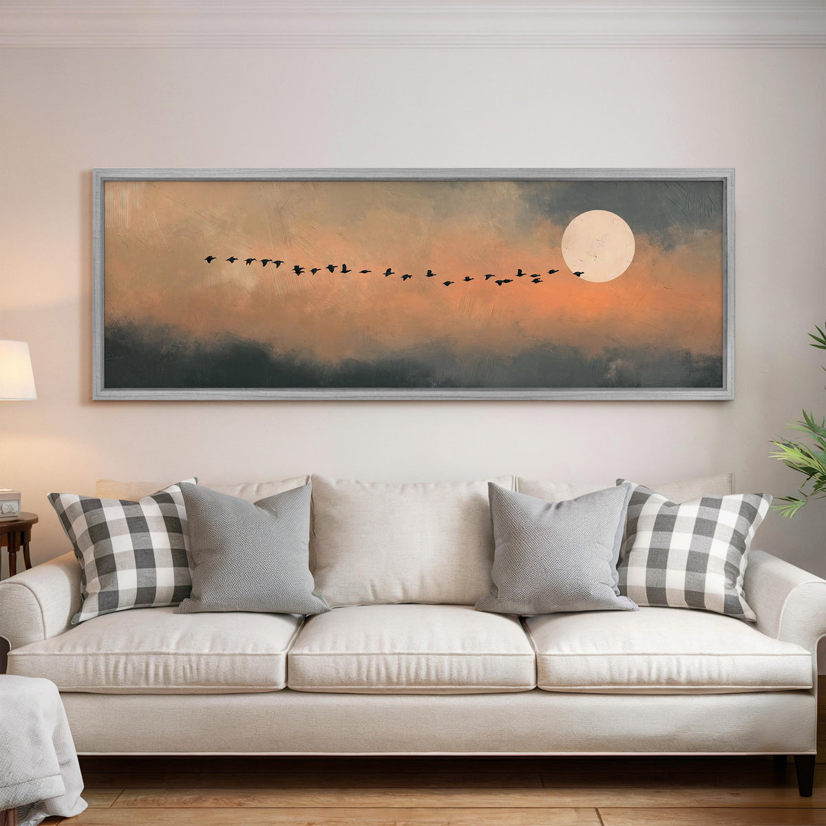 Geese flying toward the moon at twilight panoramic canvas print above a white sofa in a bright living room