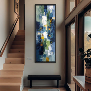 a modern art piece hanging on the wall of a hallway, with a wooden staircase and a bench in the foreground.